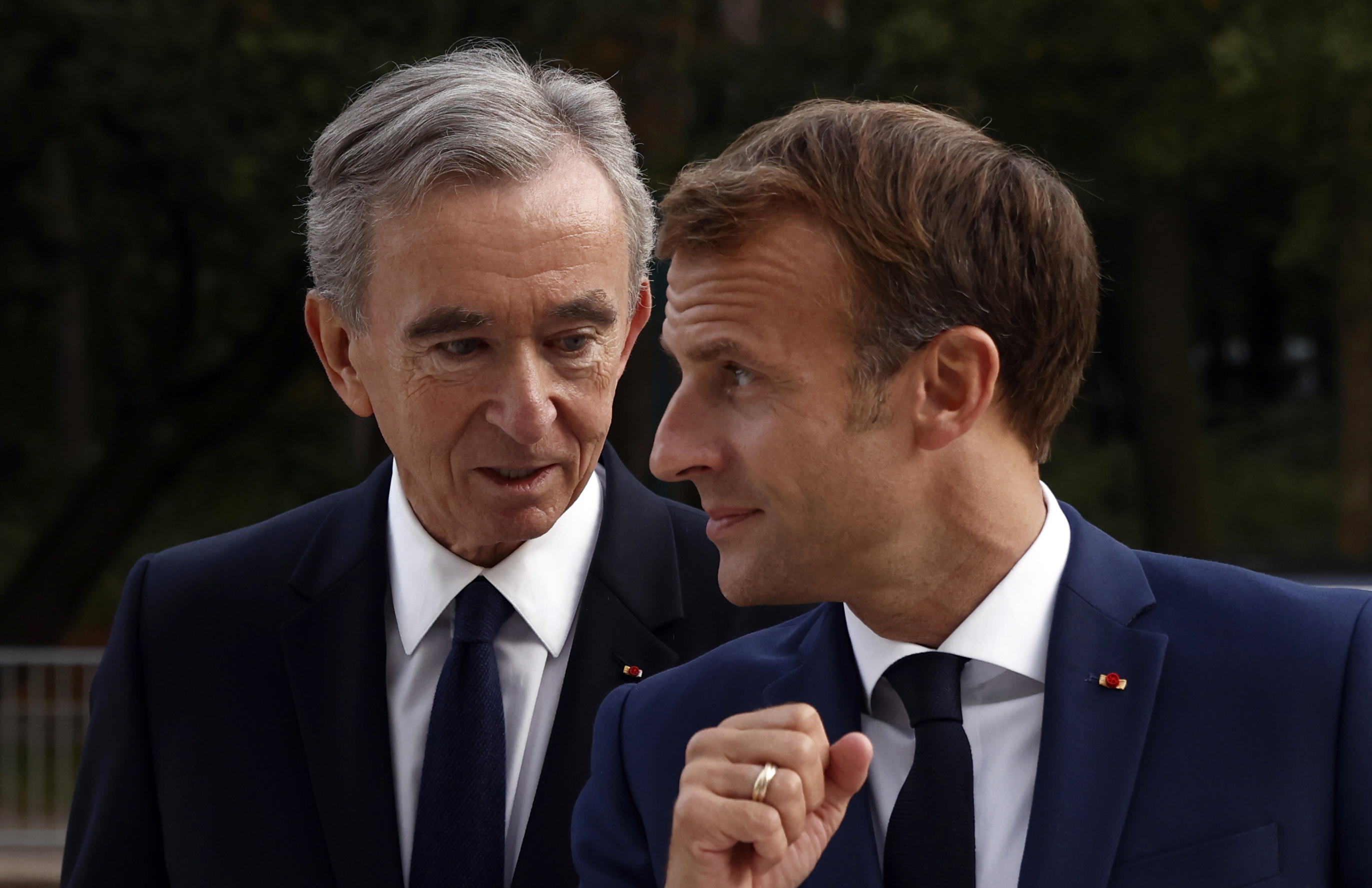 FILE - LVMH luxury group CEO Bernard Arnault, left, and French President Emmanuel Macron arrive at Fondation Louis Vuitton to visit the exhibition 'The Morozov Collection, Icons of Modern Art' in Paris, Tuesday, Sept. 21, 2021. With a major sponsorship role aimed at burnishing the image of the Paris 2024 Summer Olympic Games and the French capital, it's a new chapter in LVMH's specialty of selling exclusivity at a grand scale under its chair and CEO, Arnault. 