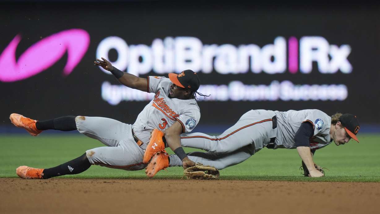 Baltimore Orioles second baseman Jorge Mateo, left, and shortstop Gunnar Henderson collide as they vie for a ball hit by Miami Marlins' Jesús Sánchez during the third inning of a baseball game, Tuesday, July 23, 2024, in Miami. Mateo was helped off the field after the play.
