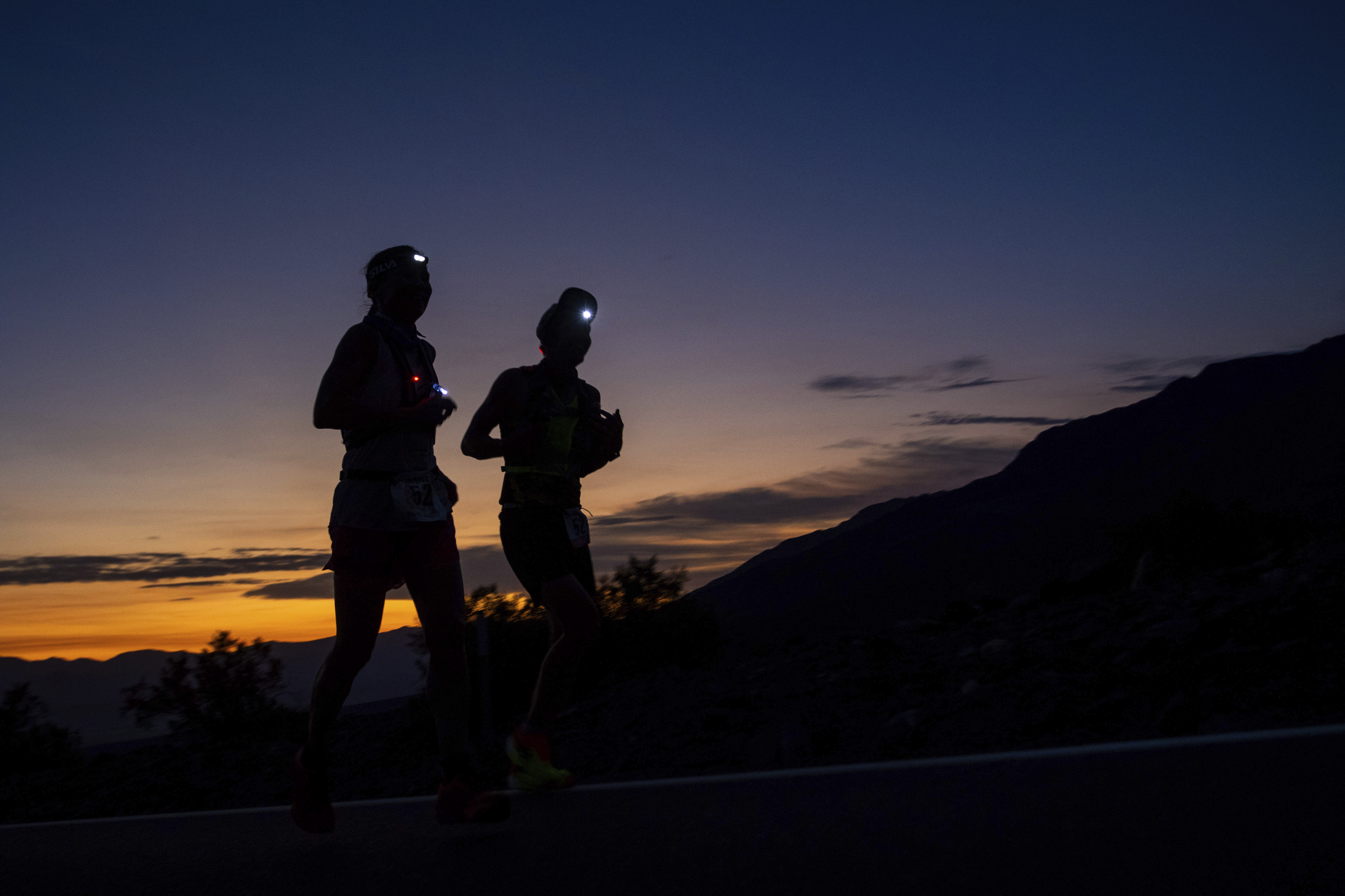 A runner and their pacer run as the sun rises behind them on California Route 190 during the Badwater 135 mile (217 kilometer) ultramarathon in Death Valley, Calif., Tuesday, July 23, 2024. 