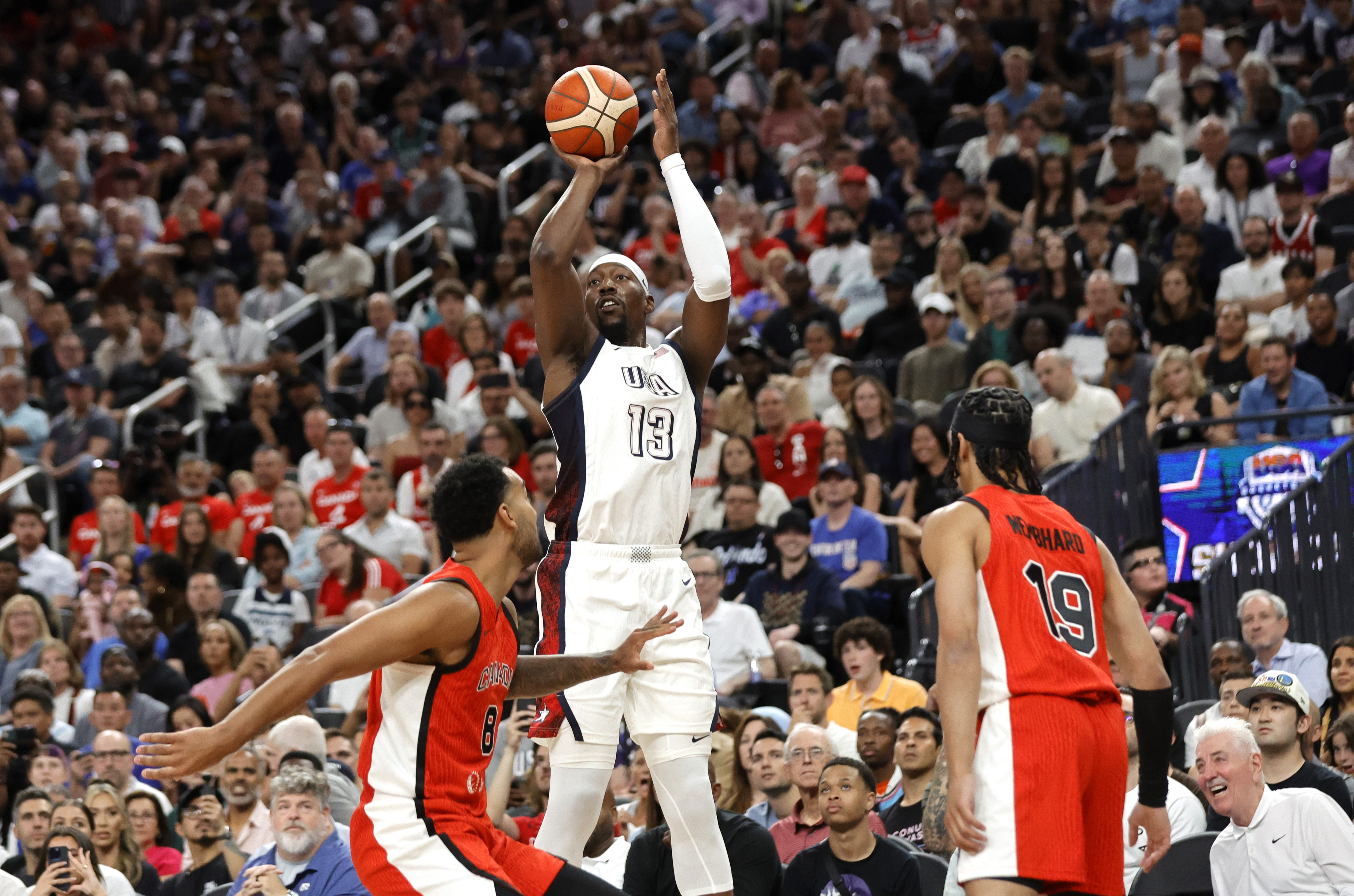 United States center Bam Adebayo (13) shoots between Canada power forward Trey Lyles (8) and point guard Andrew Nembhard (19) during the first half of an exhibition basketball game Wednesday, July 10, 2024, in Las Vegas.