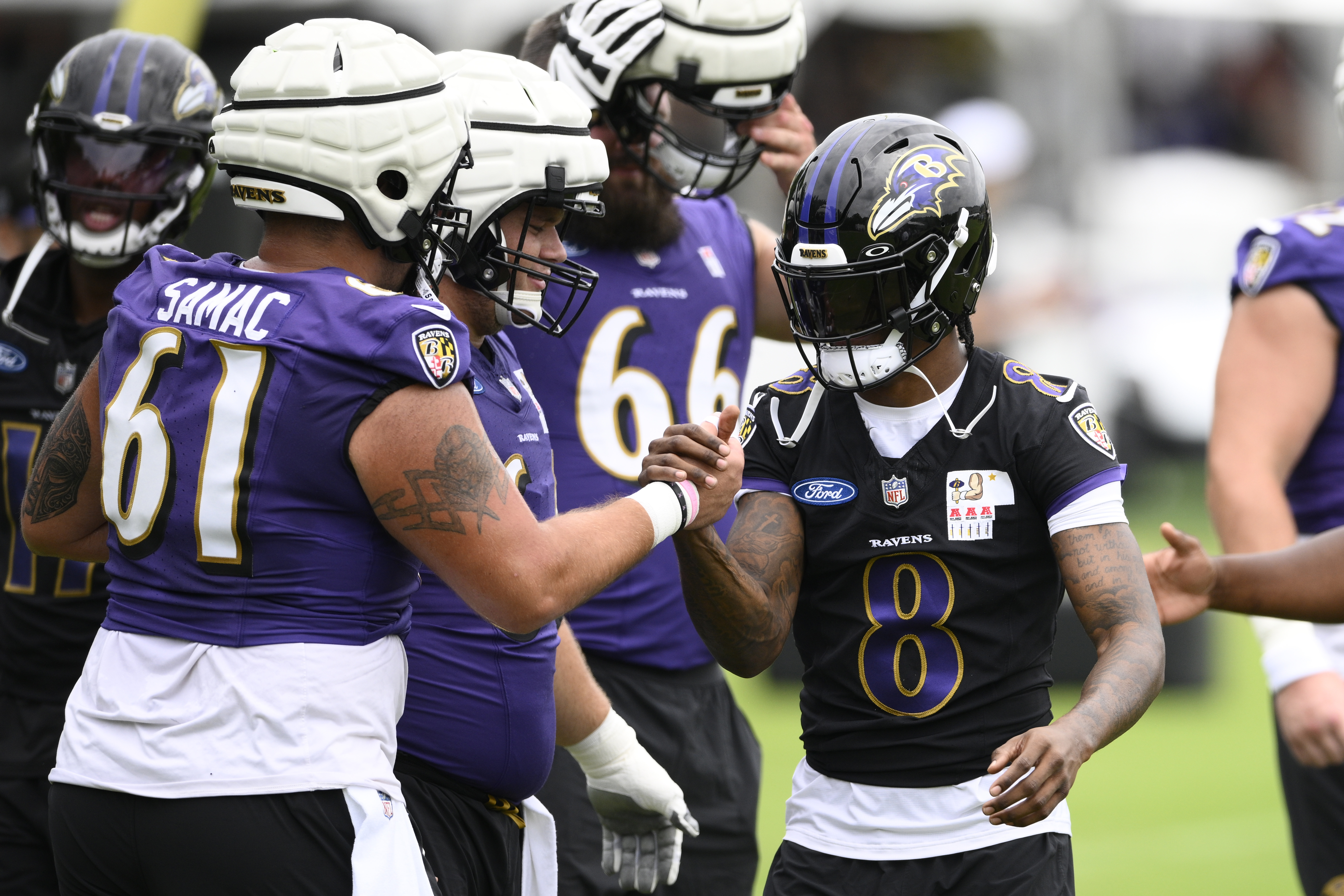 Baltimore Ravens quarterback Lamar Jackson (8) shakes hands with center Nick Samac (61) during NFL football training camp, Wednesday, July 24, 2024, in Owings Mills, Md. 