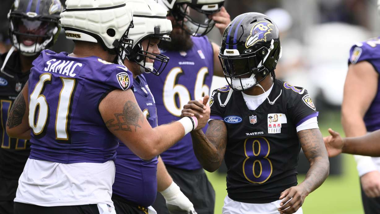 Baltimore Ravens quarterback Lamar Jackson (8) shakes hands with center Nick Samac (61) during NFL football training camp, Wednesday, July 24, 2024, in Owings Mills, Md.