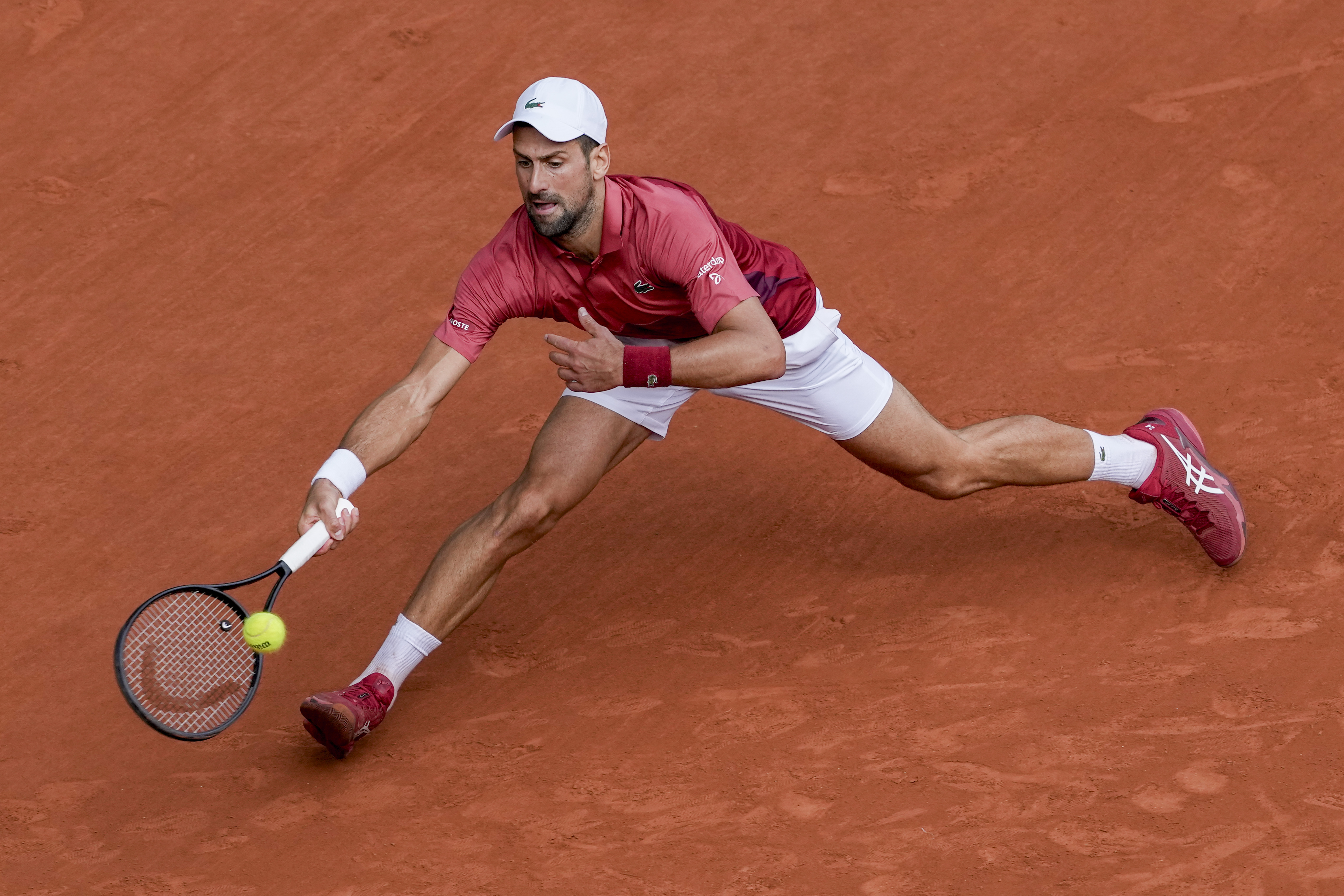 FILE - Serbia's Novak Djokovic plays a shot against Argentina's Francisco Cerundolo during their fourth-round match of the French Open tennis tournament at the Roland Garros stadium in Paris, June 3, 2024. For the first time in more than 30 years, the tennis competition at an Olympics will be held on red clay, which means players who just made the adjustment from that surface at the French Open in early June to grass at Wimbledon in early July now will need to reverse course again in short order.