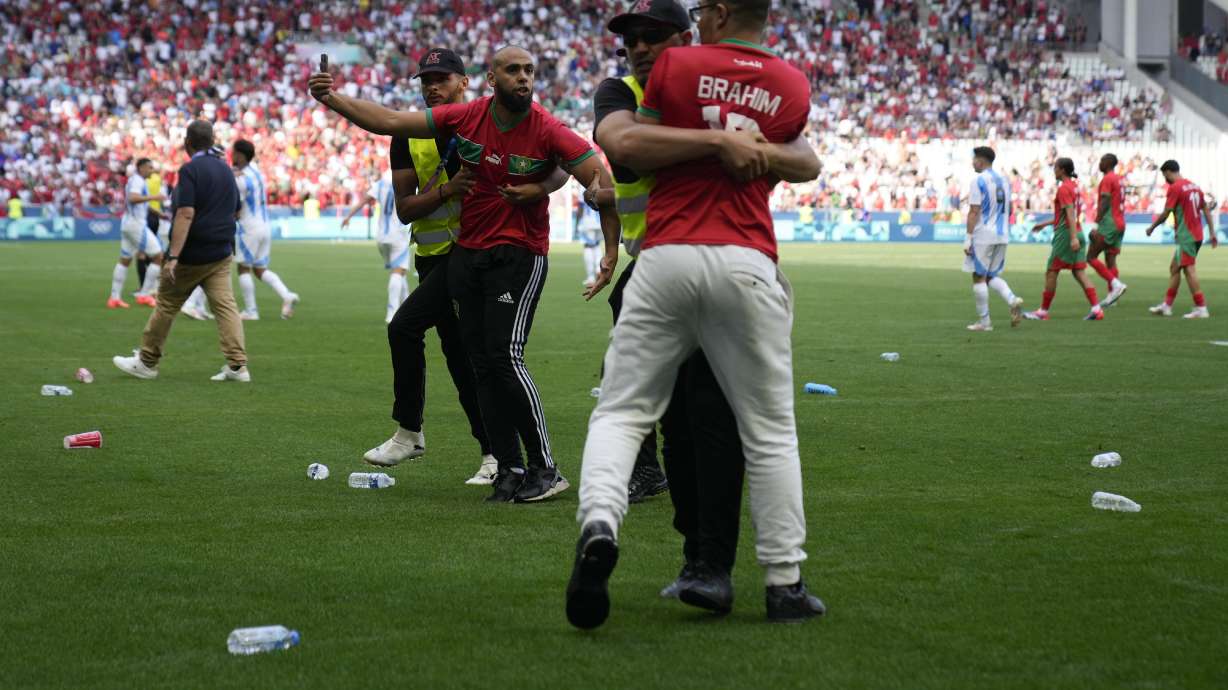 Stewards catch pitch invaders during the men's Group B soccer match between Argentina and Morocco at Geoffroy-Guichard Stadium at the 2024 Summer Olympics, Wednesday, July 24, 2024, in Saint-Etienne, France.