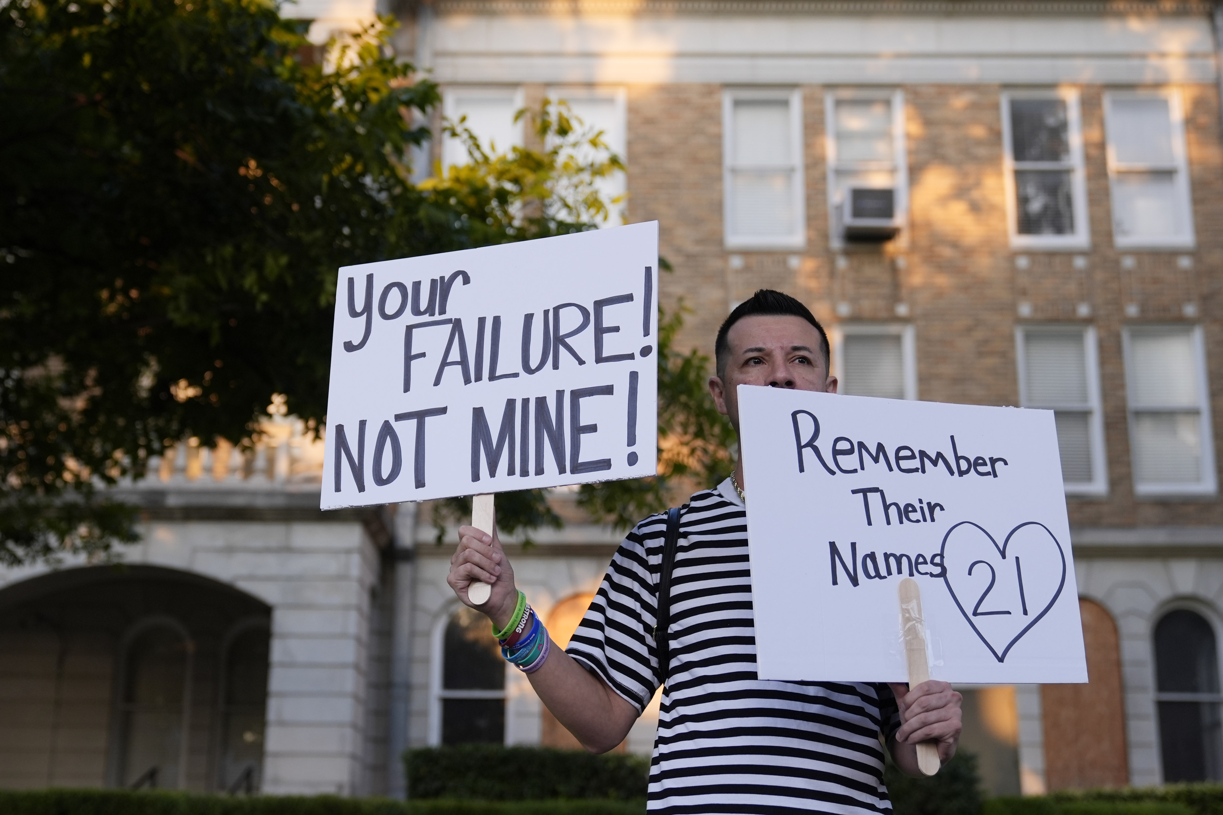 James Alvarado holds signs outside of the Uvalde County Courthouse as he shows his support for the families and victims of the shootings at Robbs Elementary School, Thursday, in Uvalde, Texas. Former Uvalde Consolidated Independent School District police officer Adrian Gonzales made his first court appearance on charges of abandoning and failing to protect children.