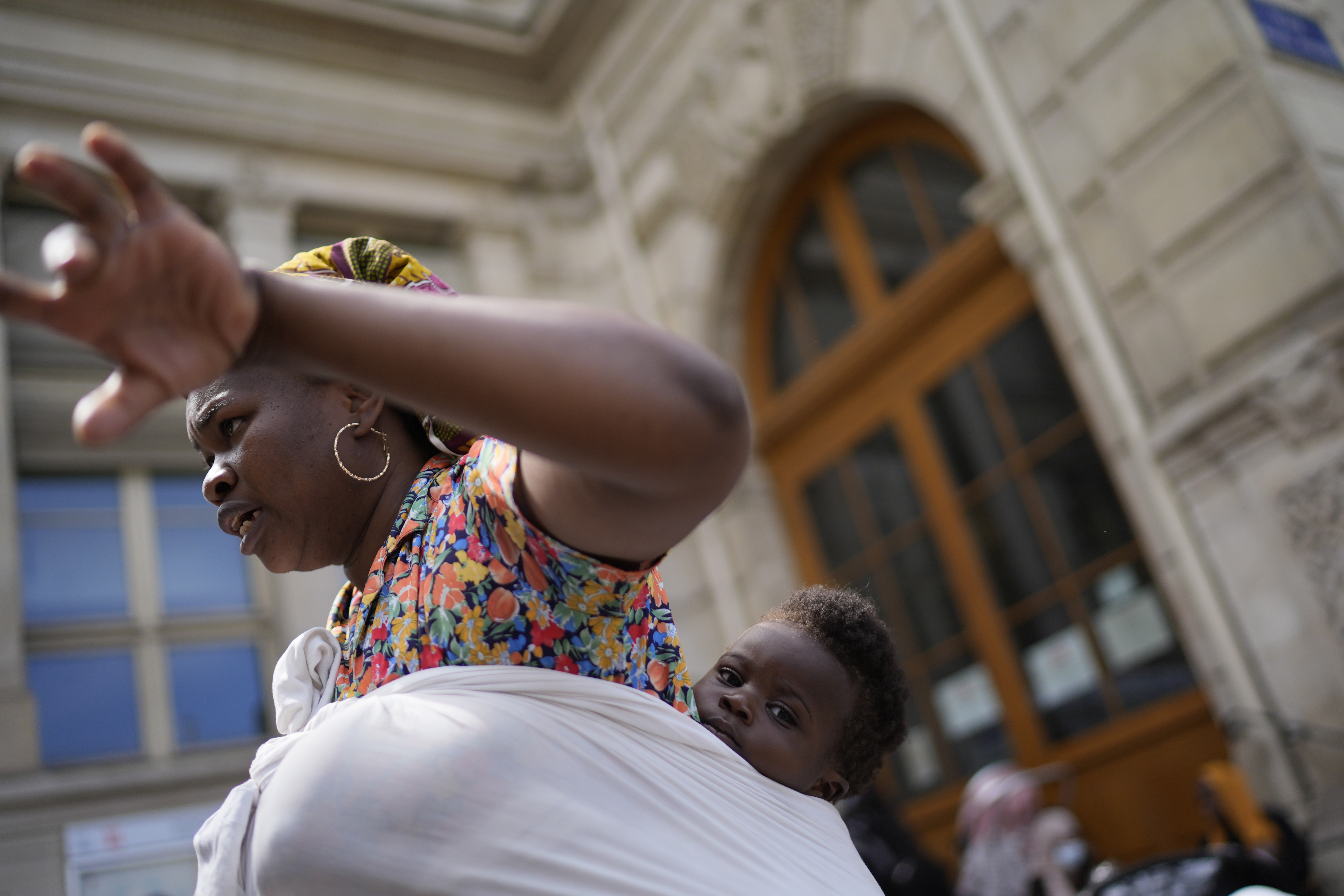 Natasha Louise Gbetie, from Burkina Faso, and her son Richard Emmanuel, attend a protest at the 2024 Summer Olympics, Thursday, July 25, 2024, in Paris, France. On the eve of the grandiose opening ceremony for the Paris Olympics, police cleared out migrants sleeping in a tent camp in the capital as social and environmental advocacy groups raise attention to criticisms of the Paris Games such as the displacement of migrants and housing issues. 