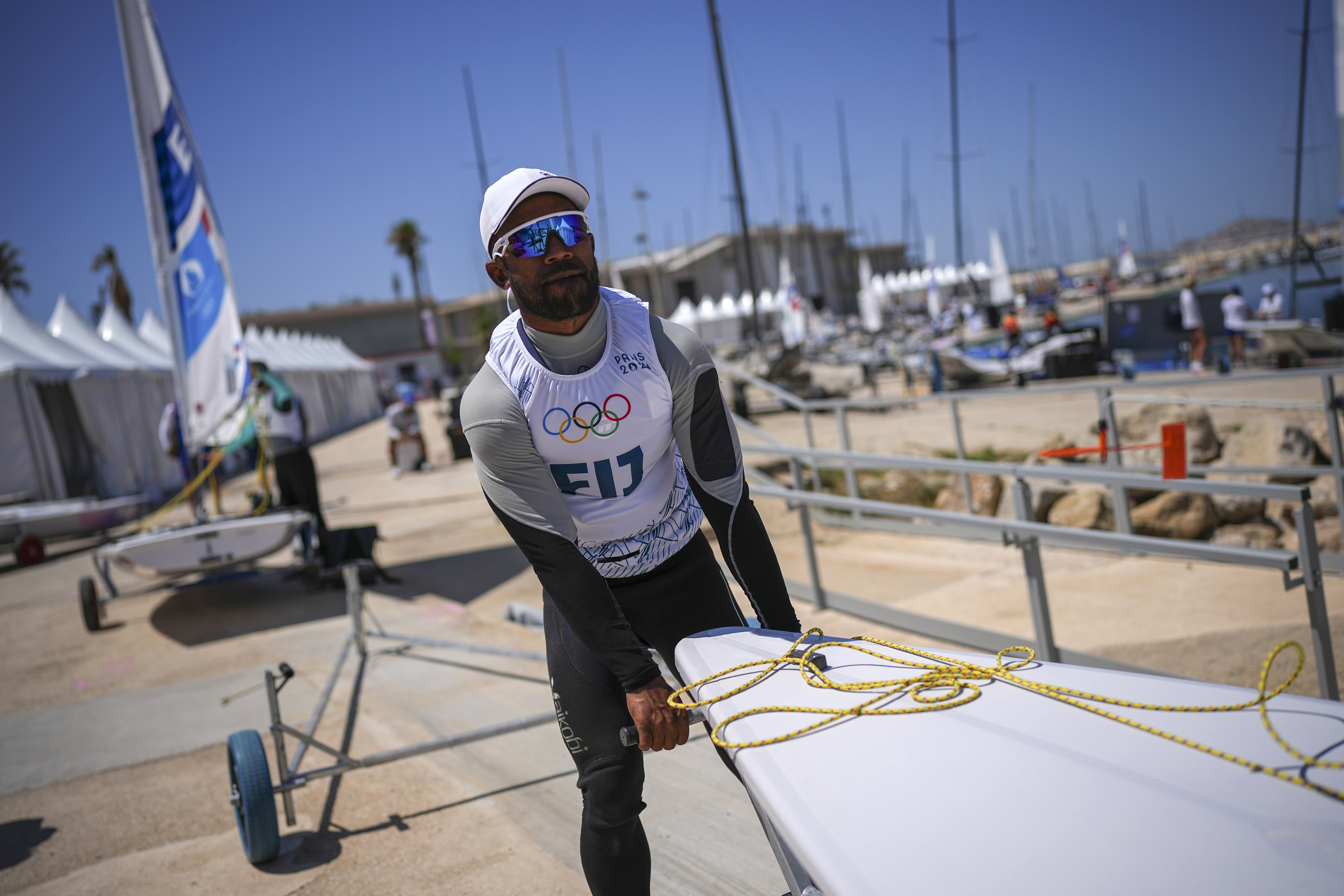 CORRECTS SPELLING OF FIRST NAME TO VILIAME NOT VILIAM - Fiji's Viliame Ratulu, competing in the men's dinghy sailing competition, prepares his dinghy for a practice session at the Marseille Marina during the 2024 Summer Olympics, Thursday, July 25, 2024, in Marseille, France. 