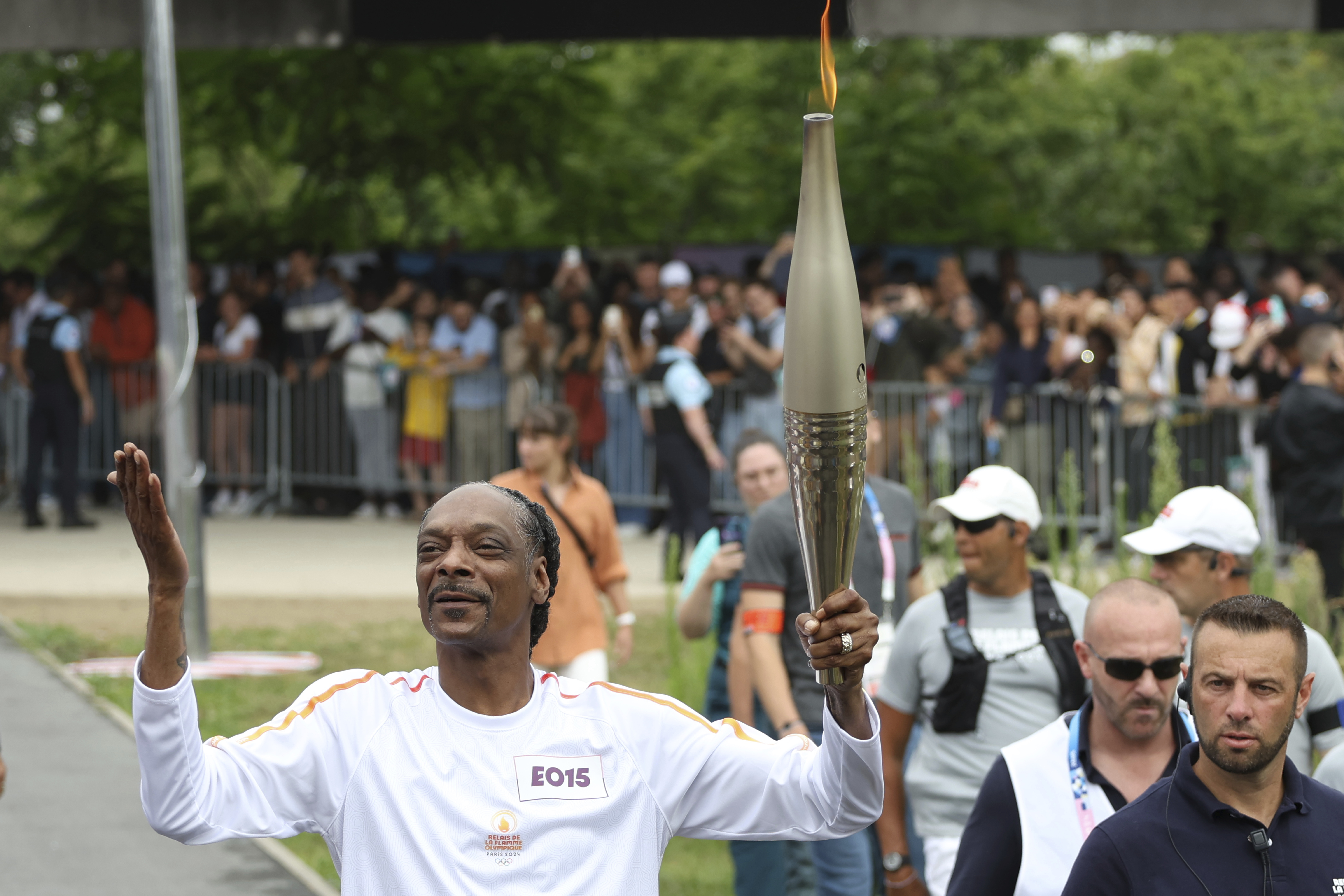 Snoop Dogg carries the Olympic torch at the 2024 Summer Olympics, Friday, July 26, 2024, in Saint-Denis, outside Paris, France. 
