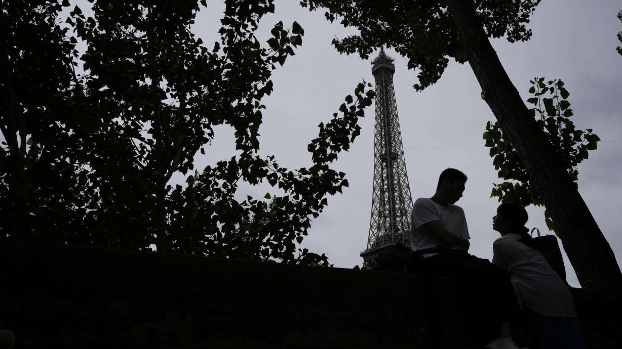 A couple waits for the opening ceremony of the 2024 Summer Olympics to begin in front of the Eiffel Tower, Friday, July 26, 2024, in Paris, France.