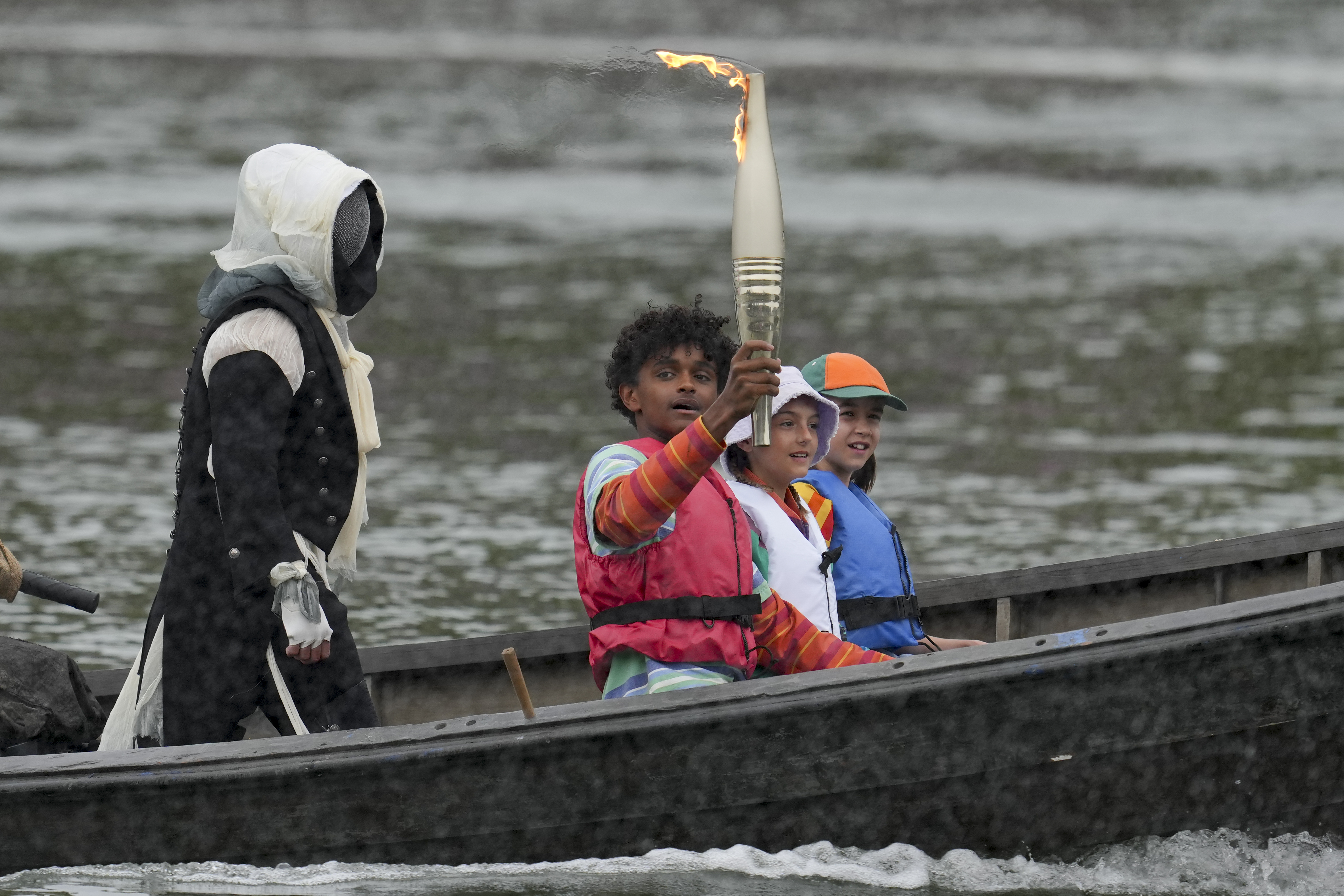 A torch is carried in Paris, France, during the opening ceremony of the 2024 Summer Olympics, Friday, July 26, 2024.