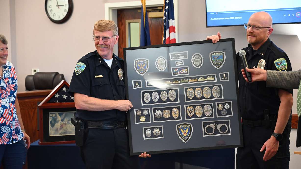 Former Centerville Police Chief Paul Child hoists his career plaque, representing a span of 41 years in law enforcement, at a recognition event July 12.