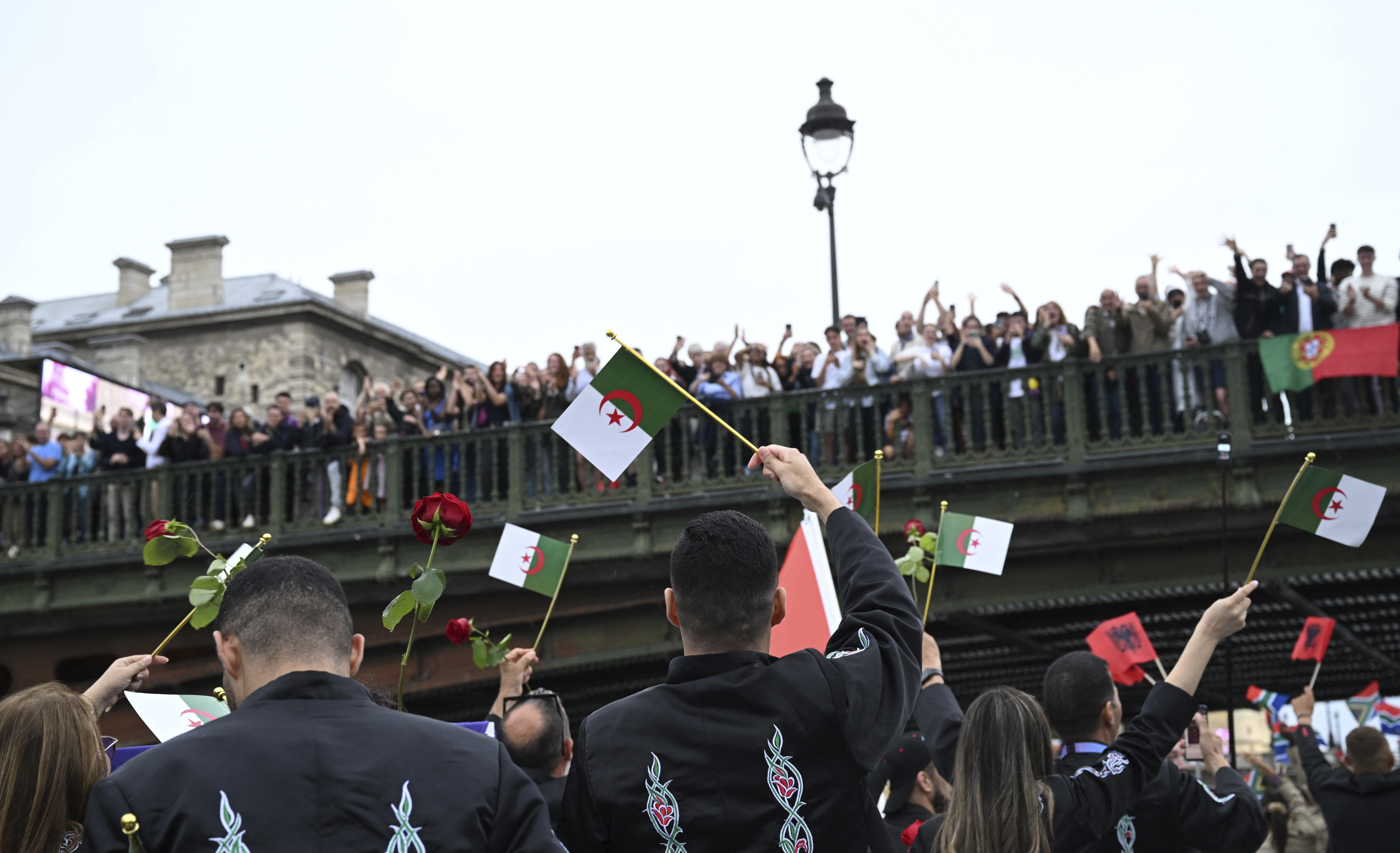 Athletes from Algeria wave flags aboard a boat on the Seine River in Paris, France, during the opening ceremony for the 2024 Summer Olympics, Friday, July 26, 2024. 