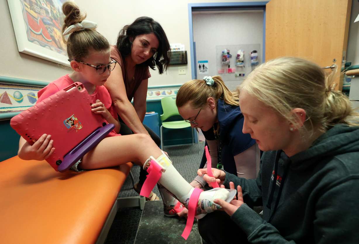 Scarlet Hill, 7, gets fitted for two stage ankle foot orthosis by Kelly Brooks, certified prosthetist-orthotist, right, and Emily Watson, pediatric orthotic and prosthetic services resident, at Shriners Children's Salt Lake City on Friday. Scarlet’s mother Cassandra Hill helps hold Scarlet’s legs.
