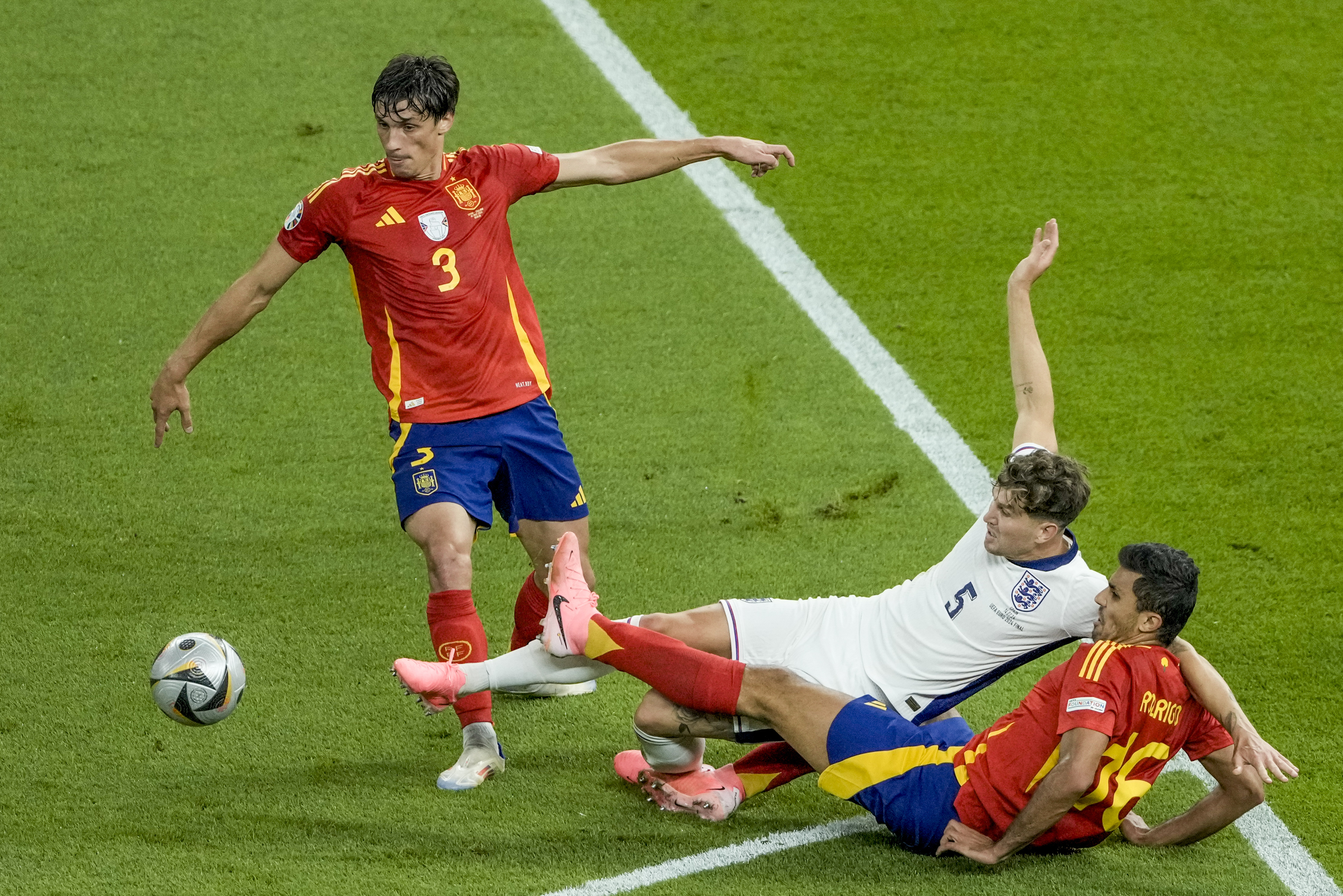 England's John Stones, center, Spain's Rodri, bottom, and Robin Le Normand fight for the ball during the final match at the Euro 2024 soccer tournament in Berlin, Germany, Sunday, July 14, 2024.