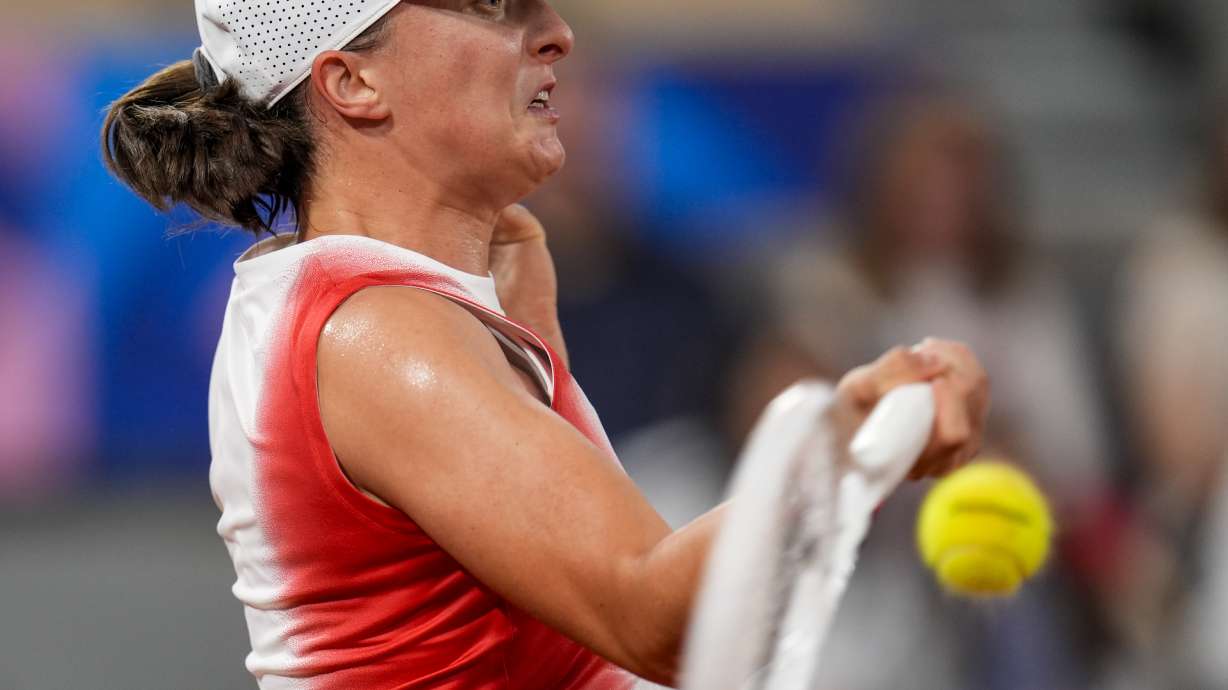 Iga Swiatek of Poland returns the ball against Irina-Camelia Begu of Romani during a women's singles tennis competition, at the 2024 Summer Olympics, Saturday, July 27, 2024, in Paris, France.