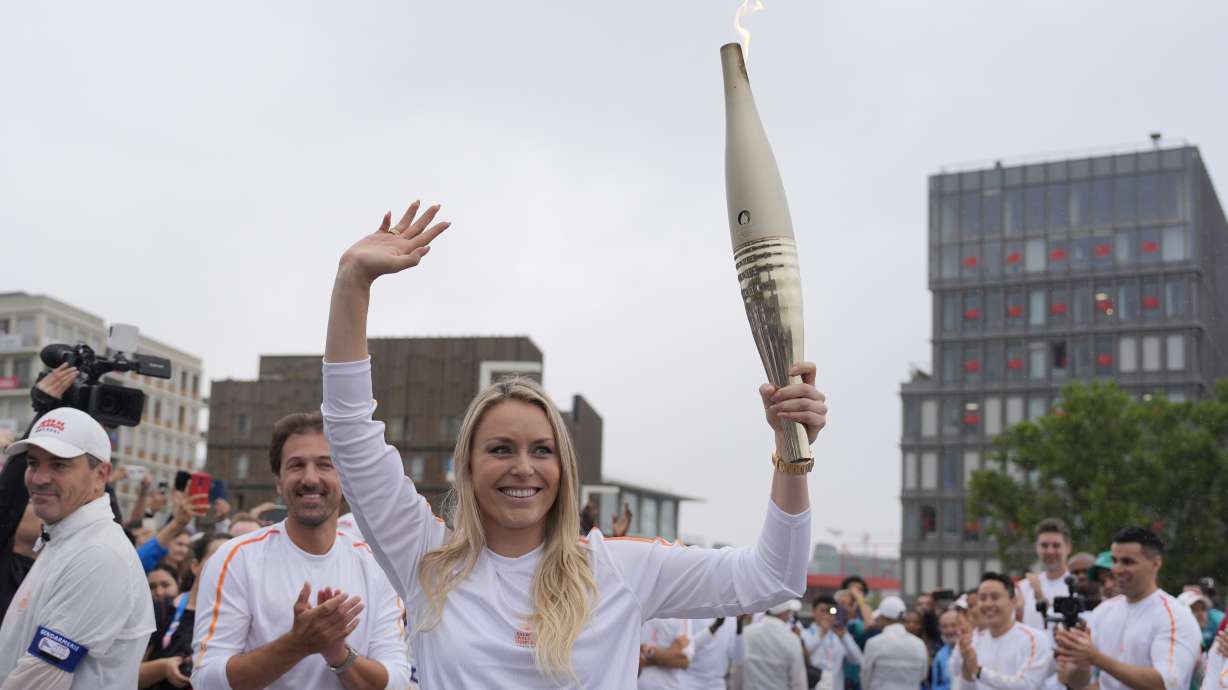 Former US skier Lindsey Vonn carries the Olympic torch in the Olympic village at the 2024 Summer Olympics, Friday, July 26, 2024, in Paris, France.