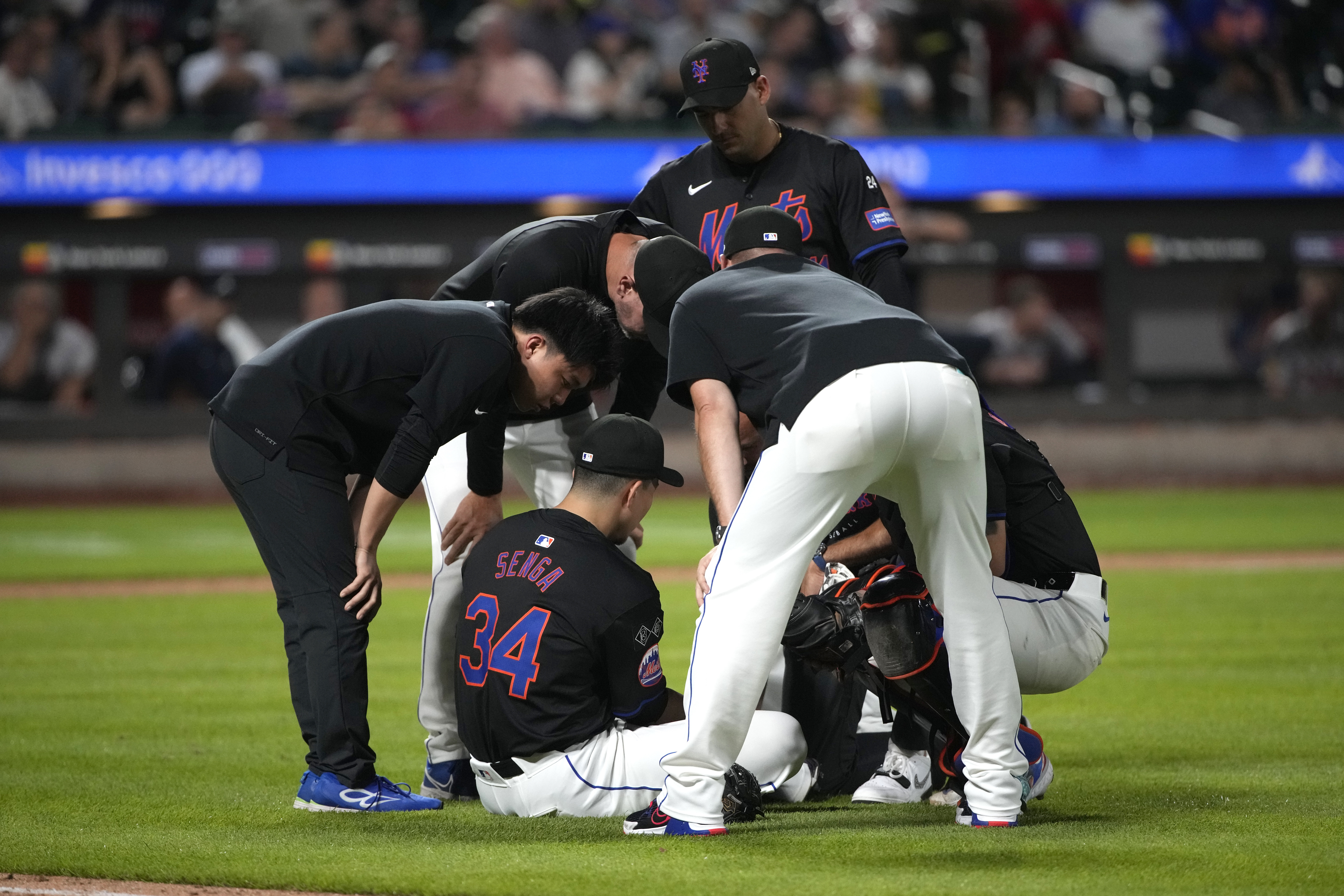 New York Mets staff members check pitcher Kodai Senga (34) after he was injured during the sixth inning of a baseball game against the Atlanta Braves, Friday, July 26, 2024, in New York.