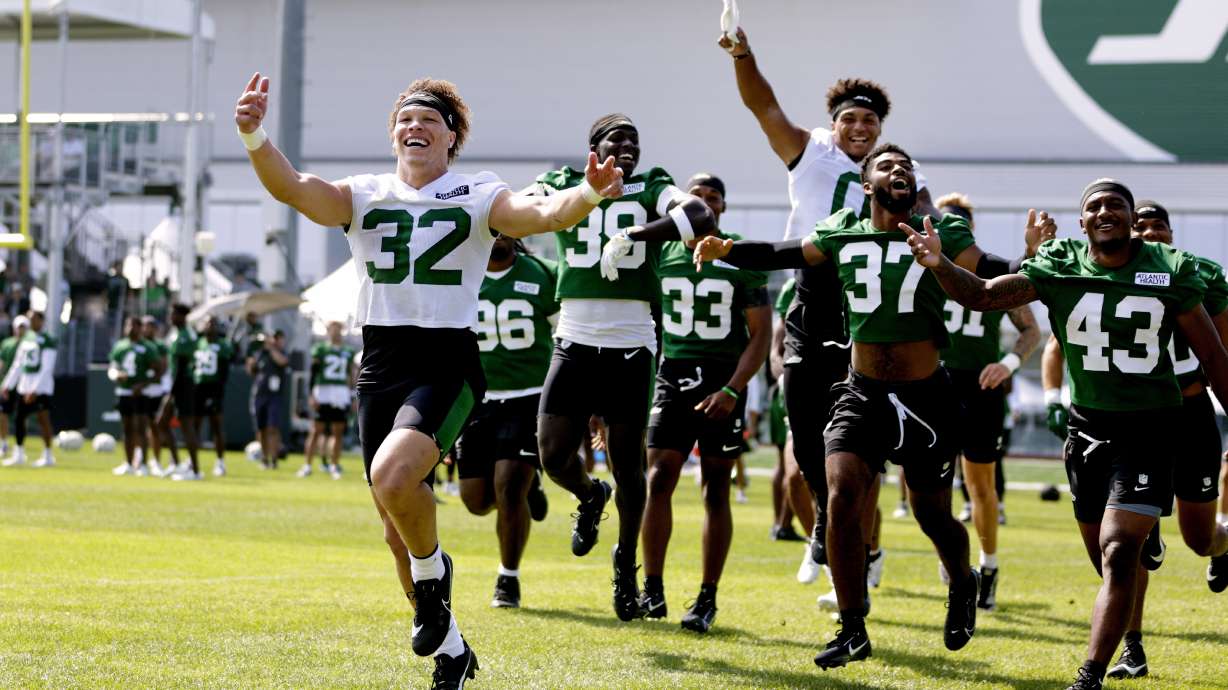 New York Jets running back Isaiah Davis (32) and teammates pump up the fans before the start of the team's NFL football training camp, Saturday, July 27, 2024, in Florham Park, N.J.