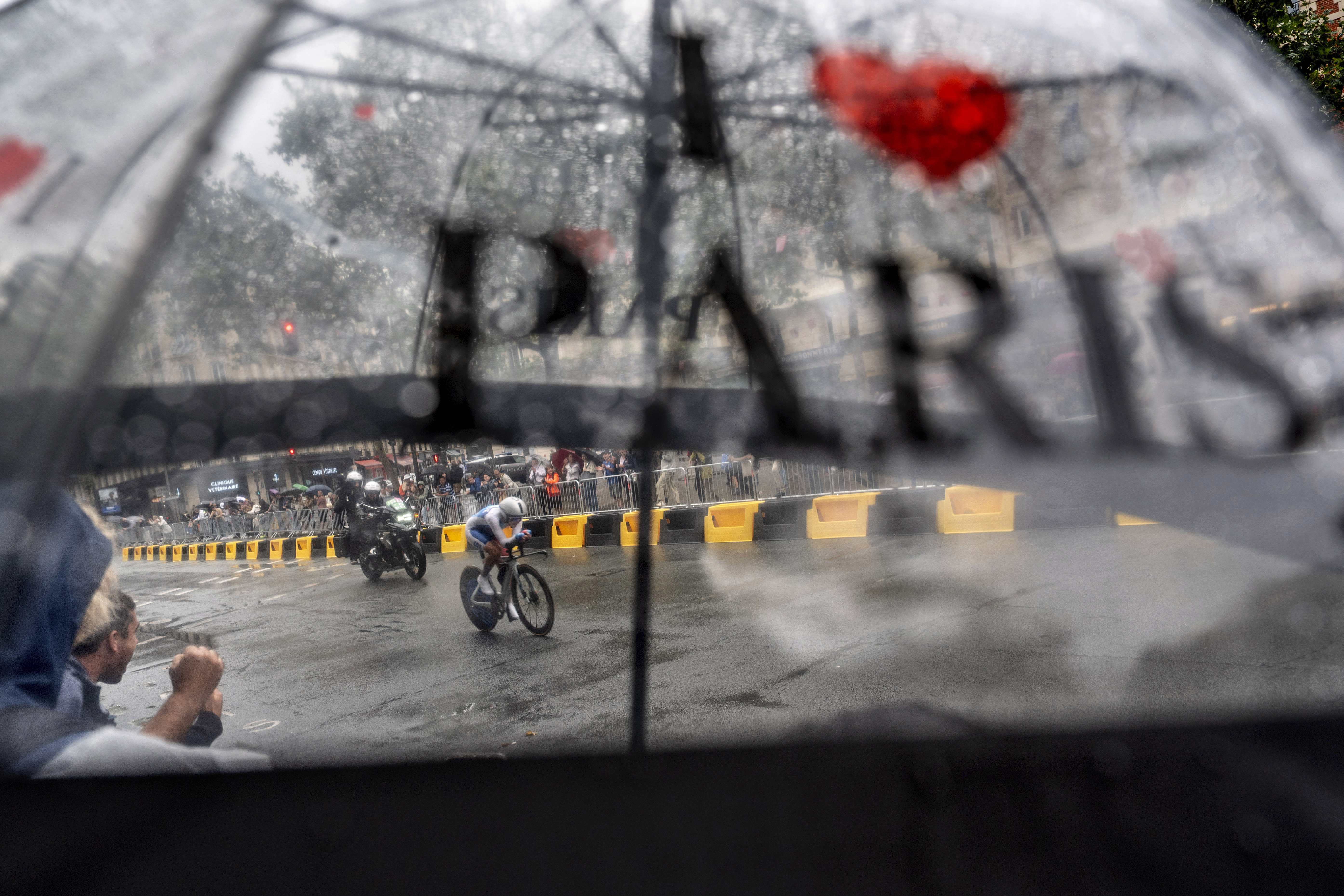 Juliette Labous, of France, is seen through a spectator's umbrella while competing in the women's cycling time trial event, at the 2024 Summer Olympics, Saturday, July 27, 2024, in Paris.