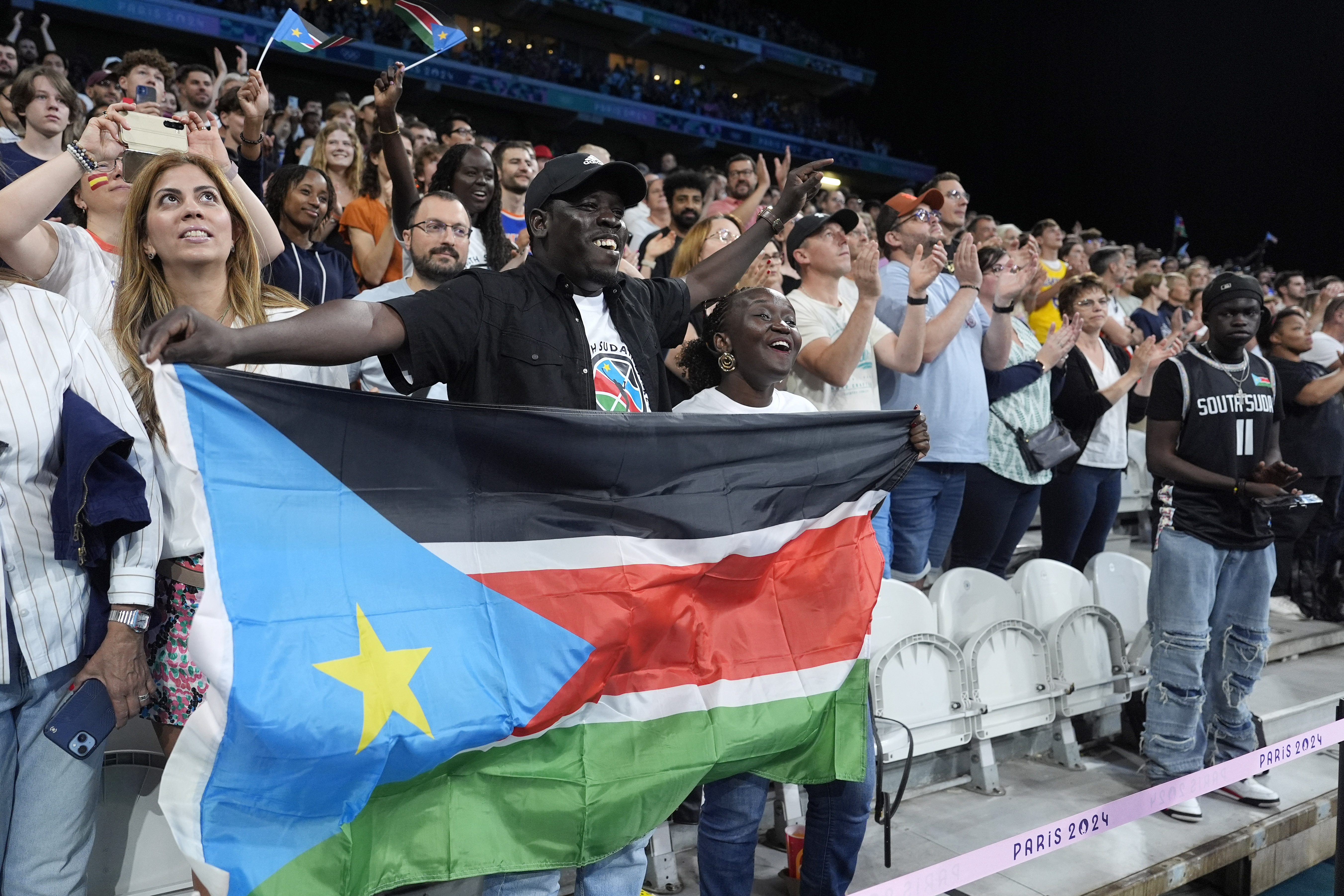 Fans are seen during a delay in the South Sudan national anthem prior to a men's basketball game against Puerto Rico at the 2024 Summer Olympics, Sunday, July 28, 2024, in Villeneuve-d'Ascq, France.