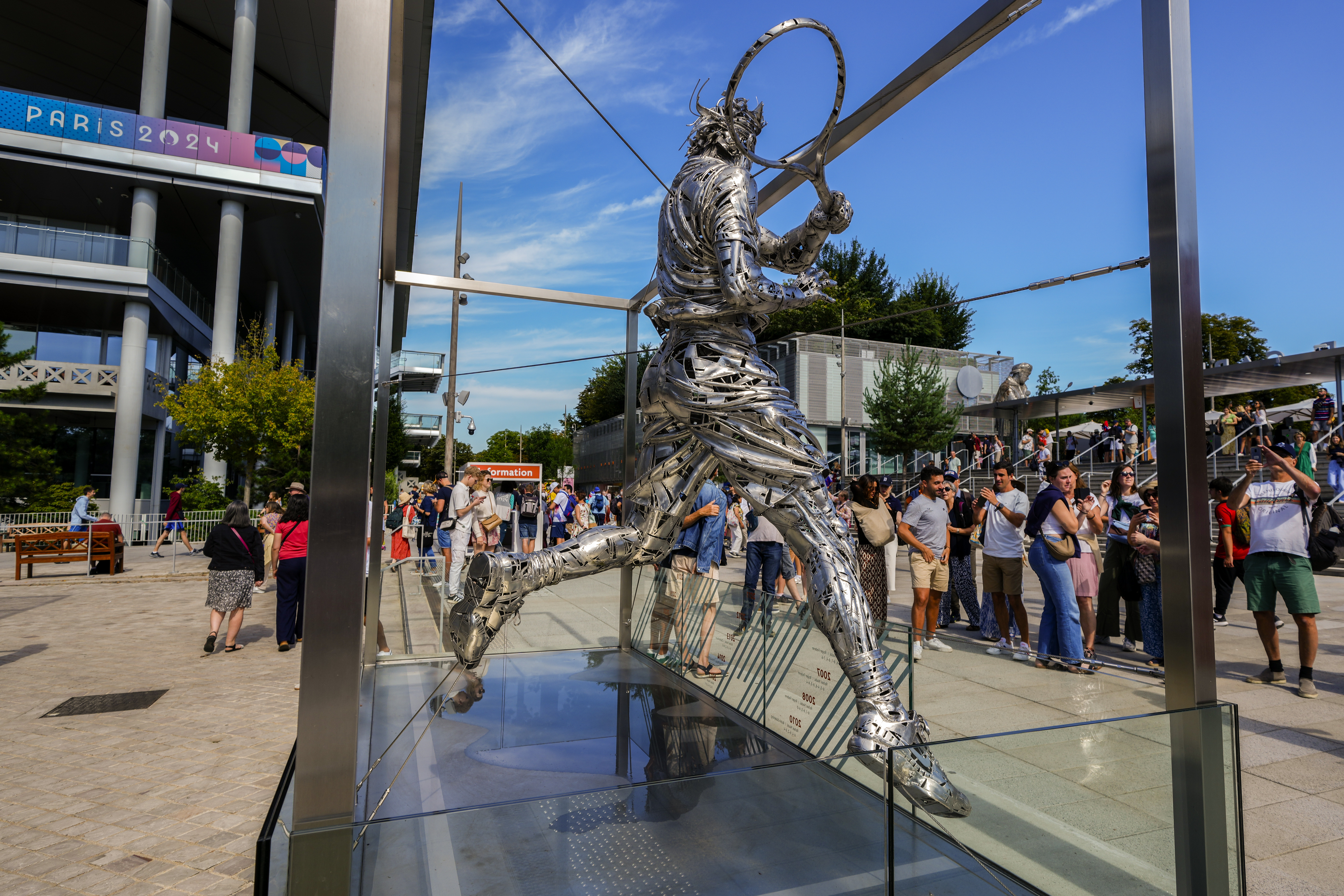 People gather next to the statue of Spanish artist Jordi Diez representing Spain's Rafael Nadal at the Roland Garros stadium during the 2024 Summer Olympics, Sunday, July 28, 2024, in Paris, France. 