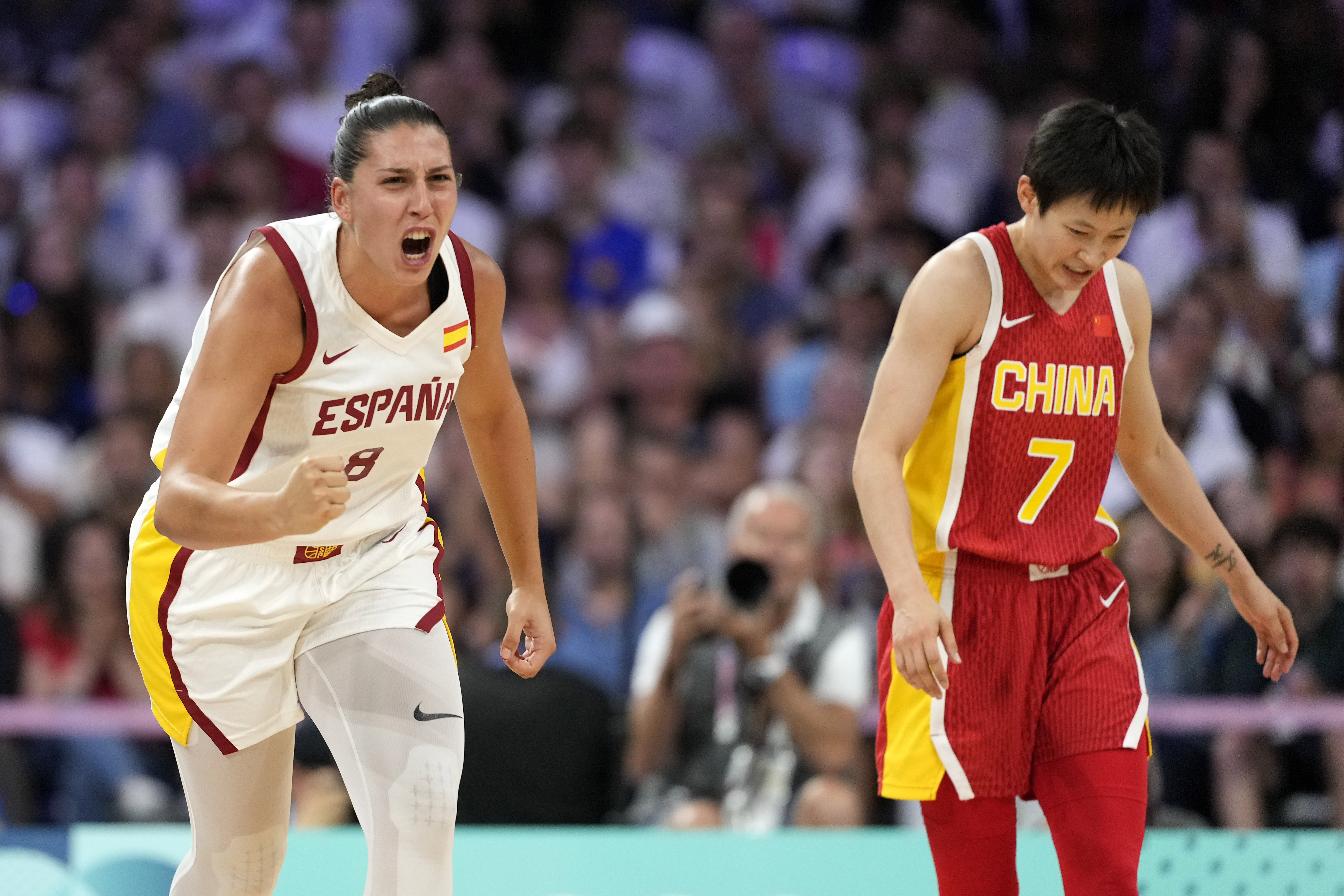 Maria Araujo, left, of Spain, celebrates a three-point basket as Liewi Yang, of China, stands by in a women's basketball game at the 2024 Summer Olympics, Sunday, July 28, 2024, in Villeneuve-d'Ascq, France. 