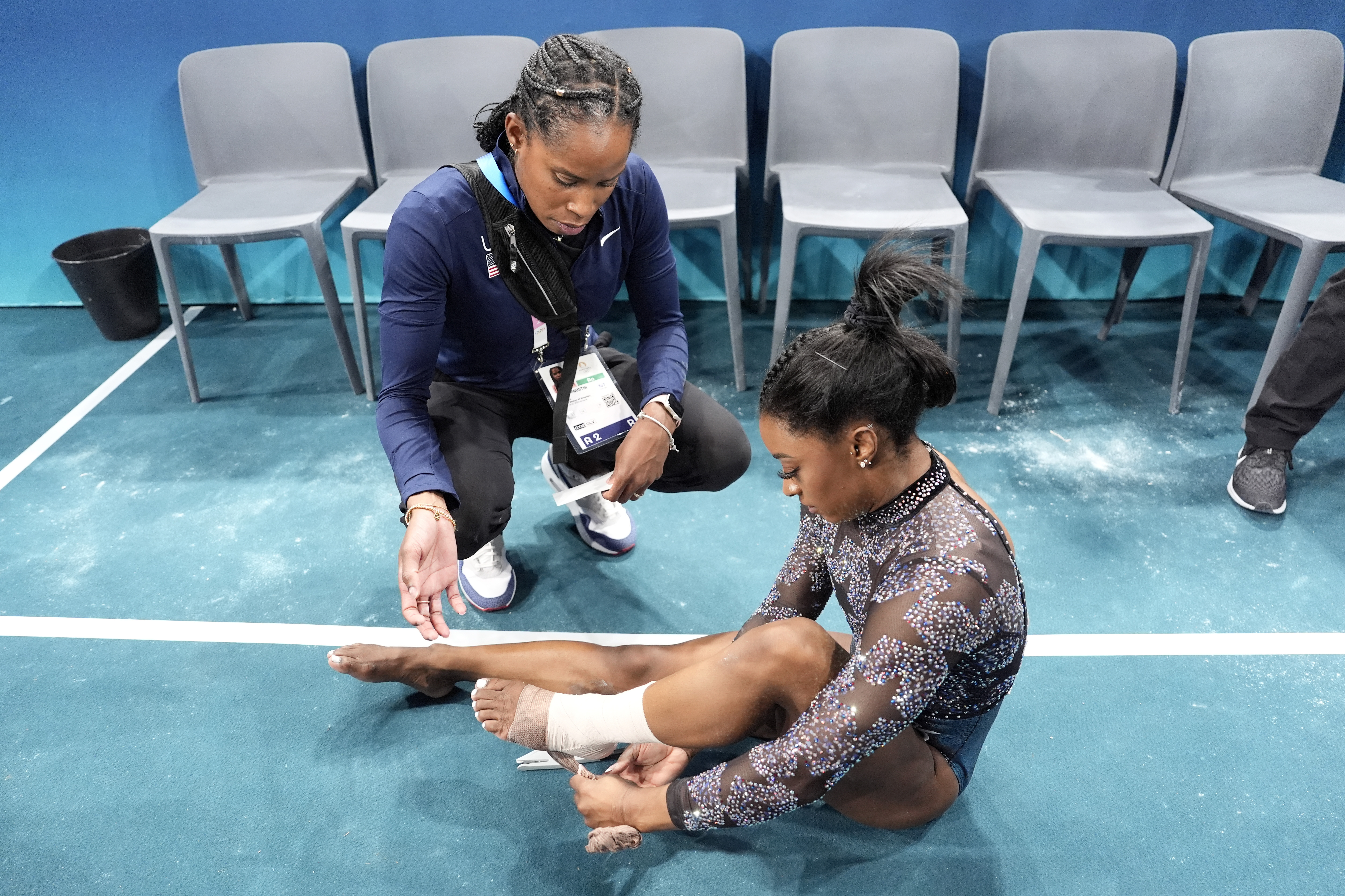 Simone Biles of United States, has her ankle taped after competing on the uneven bars during a women's artistic gymnastics qualification round at Bercy Arena at the 2024 Summer Olympics, Sunday, July 28, 2024, in Paris, France. 
