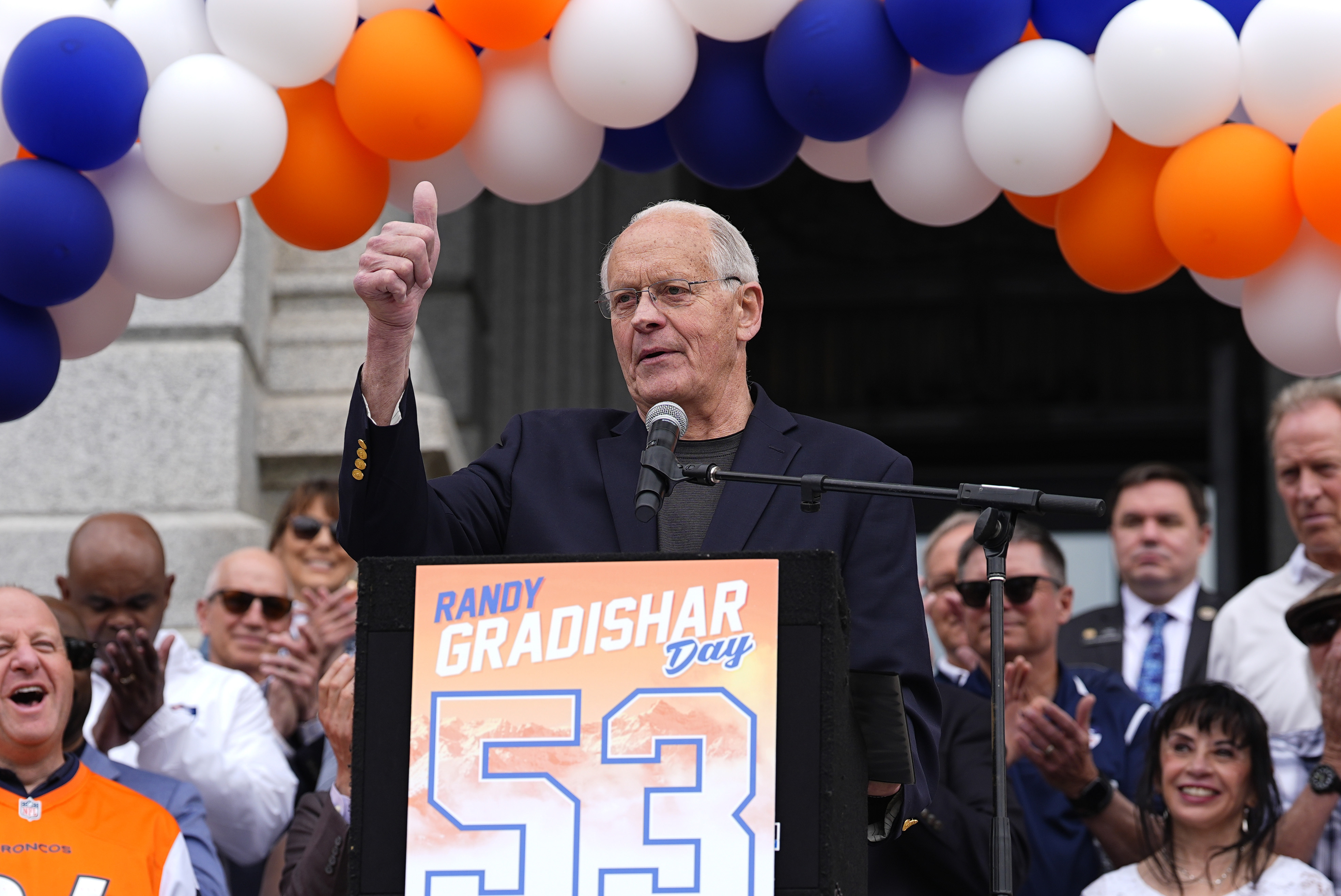 FILE - Denver Broncos Ring of Fame linebacker Randy Gradishar, center, speaks during a celebration outside the State Capitol to mark his inclusion in the NFL Pro Football Hall of Fame Class of 2024, Friday, May 3, 2024, in Denver. Gradishar is the first member of the Broncos' famed “Orange Crush” defense to be enshrined in the Pro Football Hall of Fame. 