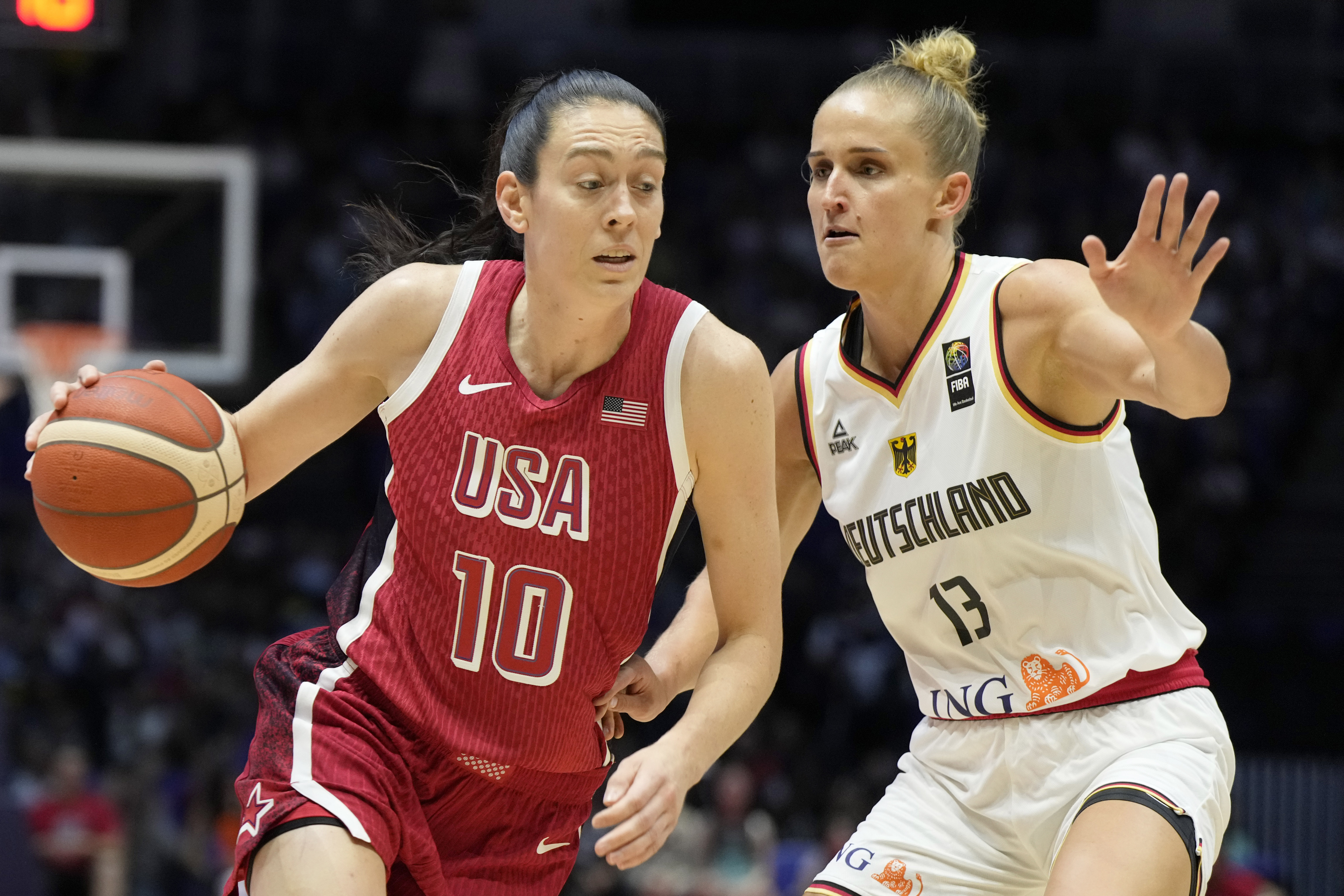 United States' Breanna Stewart, left, drives around Germany's Leonie Fiebich during a women's exhibition basketball game between the United States and Germany at the O2 Arena in London, Tuesday, July 23, 2024. 