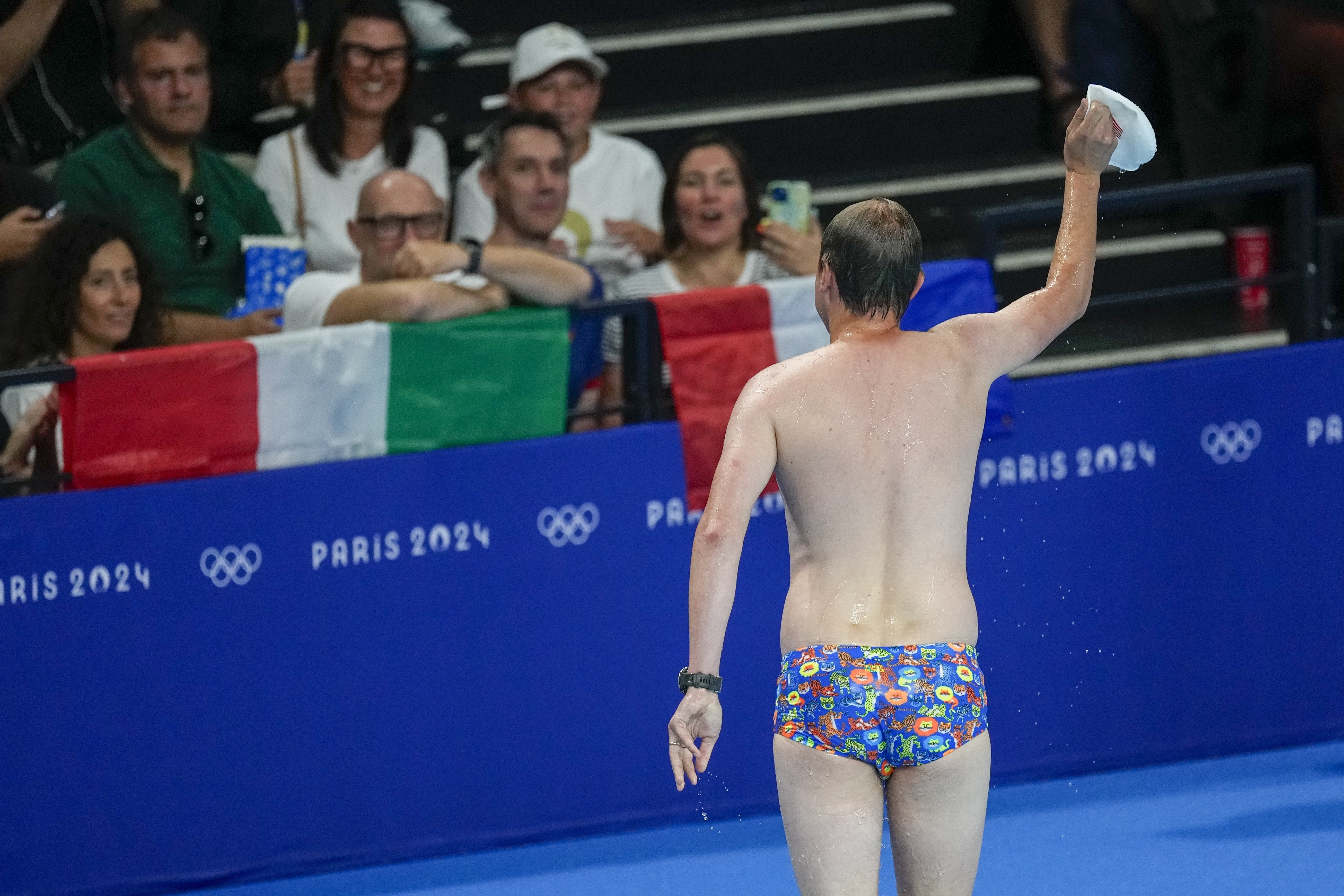 A lifeguard gestures to the crowd after retrieving United States swimmer Emma Webber's swimming cap that happened to have been left at the bottom of the pool during the morning session at the 2024 Summer Olympics, Sunday, July 28, 2024, in Nanterre, France.
