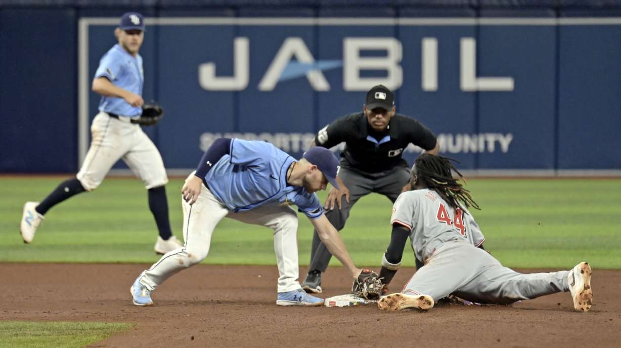 Tampa Bay Rays shortstop Taylor Walls, left, and umpire Edwin Moscoso, center, watch as Cincinnati Reds' Elly De La Cruz (44) bats the tag from Brandon Lowe for a stolen base during the sixth inning of a baseball game, Sunday, July 28, 2024, in St. Petersburg, Fla.