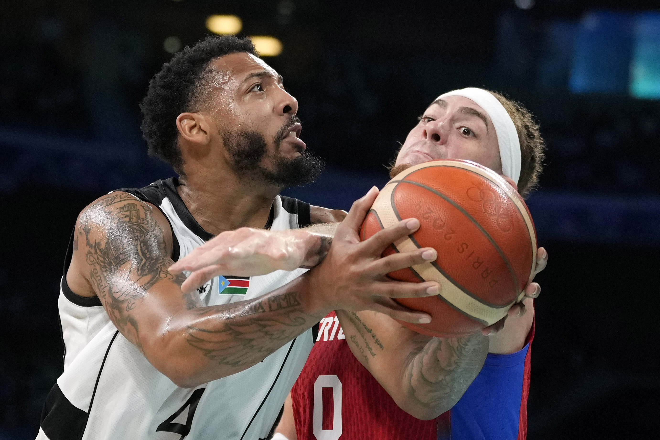 Isaiah Pineiro, right, of Puerto Rico, tries to stop a shot by Carlik Jones, of South Sudan, in a men's basketball game at the 2024 Summer Olympics, Sunday, July 28, 2024, in Villeneuve-d'Ascq, France. 