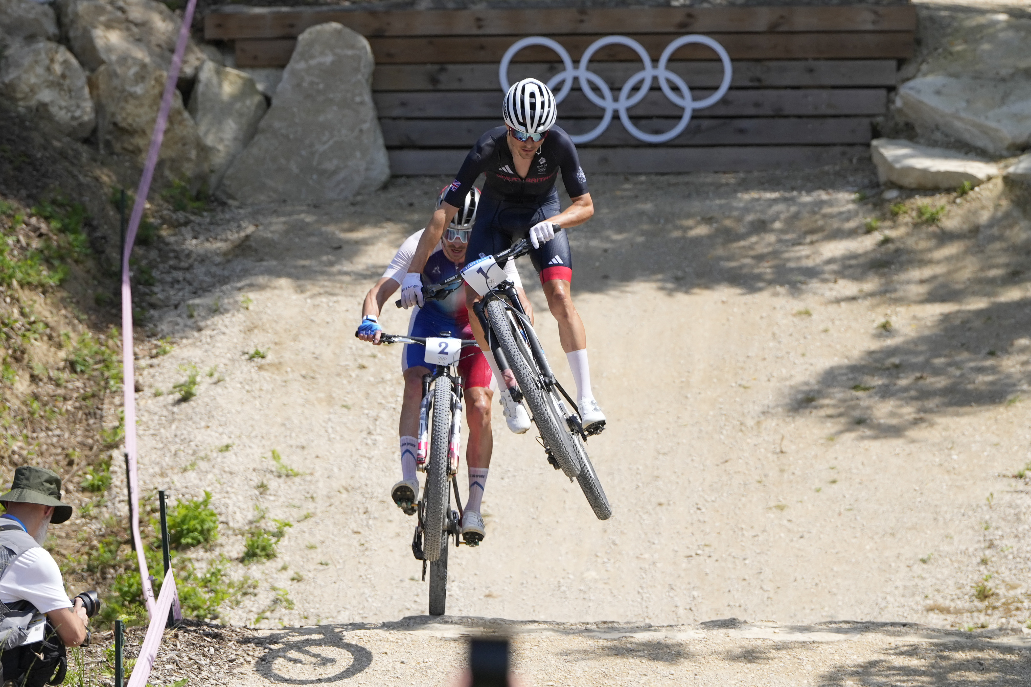 Thomas Pidcock, of Britain, is airborne as he leads Victor Koretzky, of France, during the men's mountain bike race, at the 2024 Summer Olympics, Monday, July 29, 2024, in Elancourt, France. .