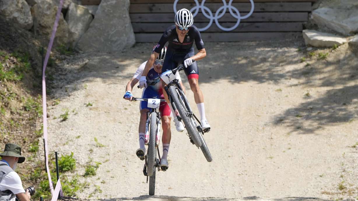 Thomas Pidcock, of Britain, is airborne as he leads Victor Koretzky, of France, during the men's mountain bike race, at the 2024 Summer Olympics, Monday, July 29, 2024, in Elancourt, France. .