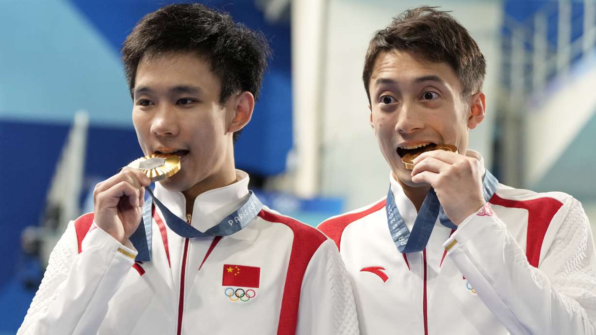 China's Lian Junjie and Yang Hao celebrate on the podium after winning the gold medal in the men's synchronised 10m platform diving final at the 2024 Summer Olympics, Monday, July 29, 2024, in Saint-Denis, France.