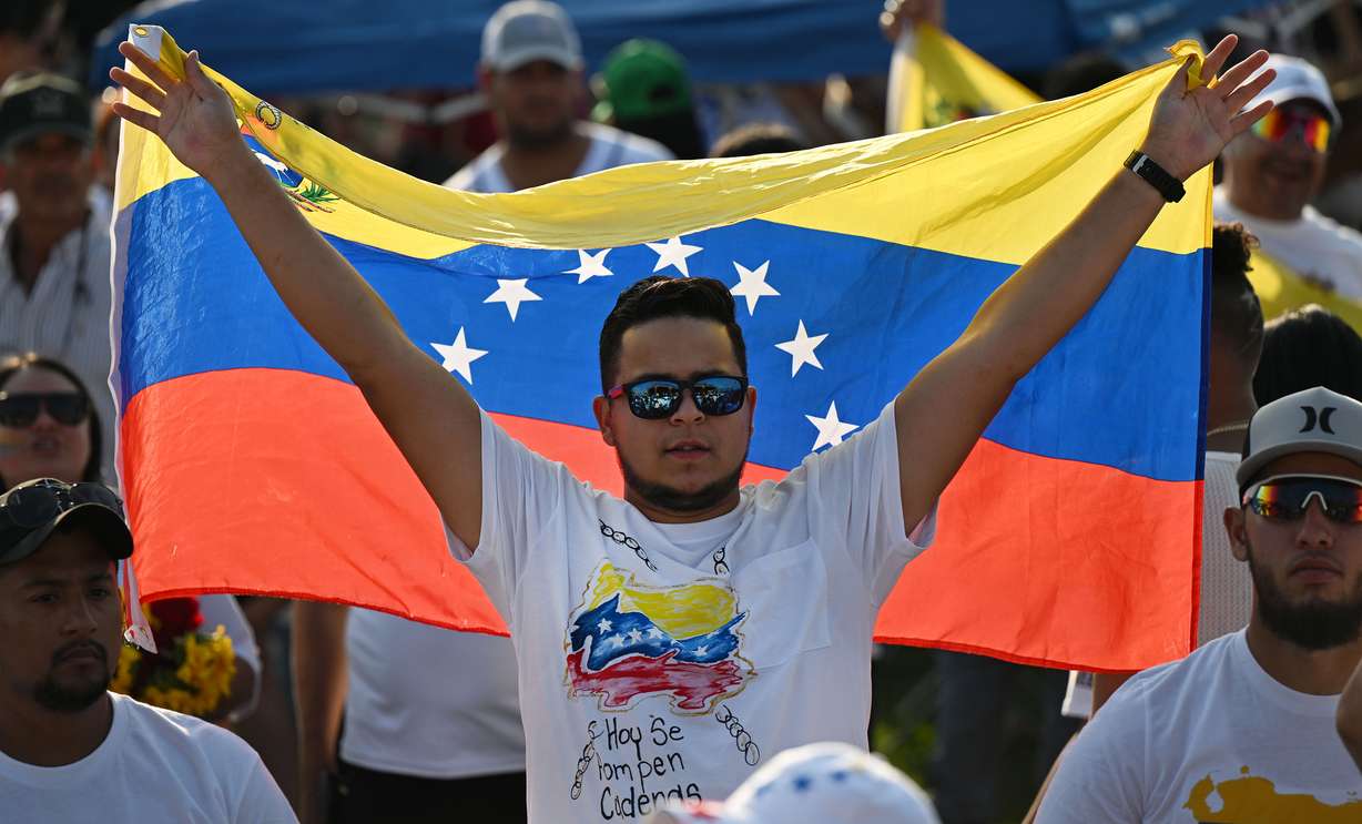 A man holds up a Venezuelan flag as Venezuelans celebrate the election in their home country in Herriman on Sunday.