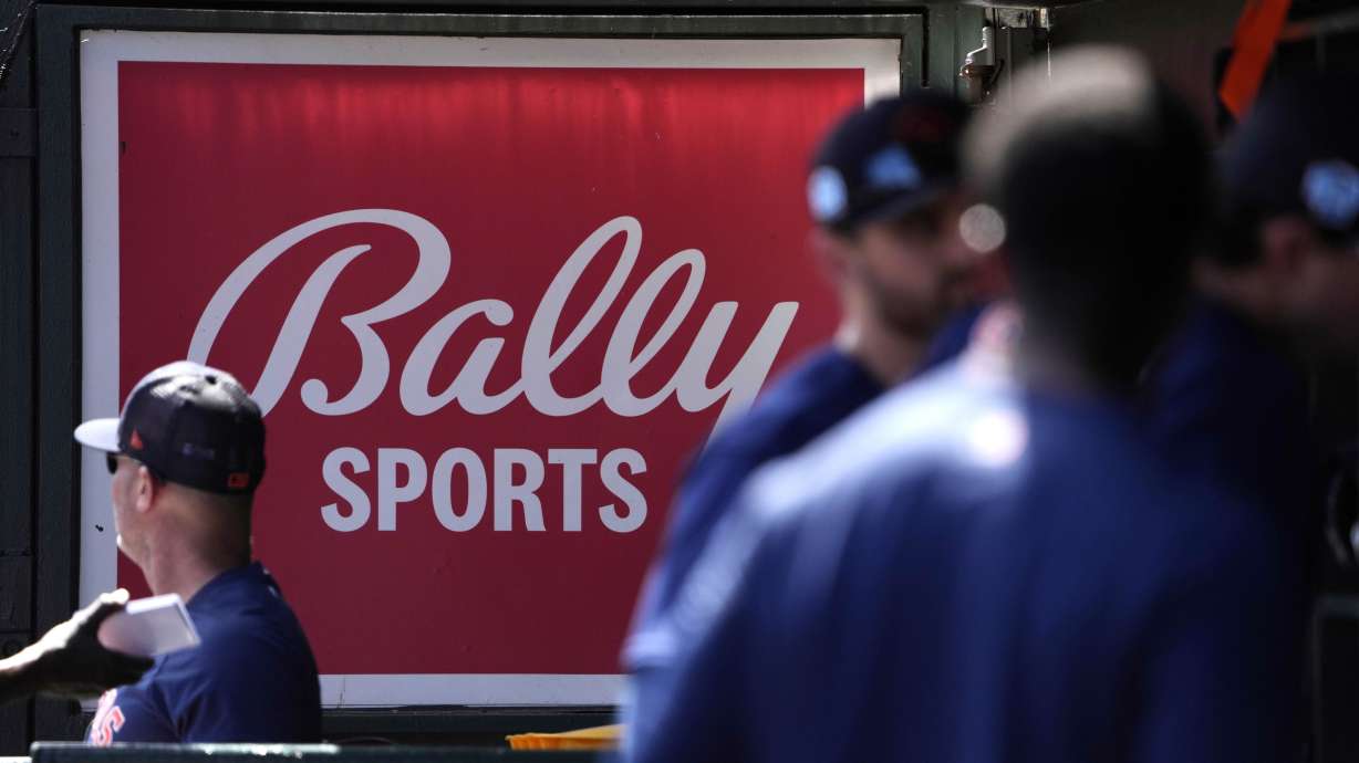 FILE -A Bally Sports sign hangs in a dugout before a spring training baseball game between the St. Louis Cardinals and the Houston Astros, March 2, 2023, in Jupiter, Fla. Most Comcast subscribers will be able to watch their favorite sports teams again after it reached an agreement with their distributor.