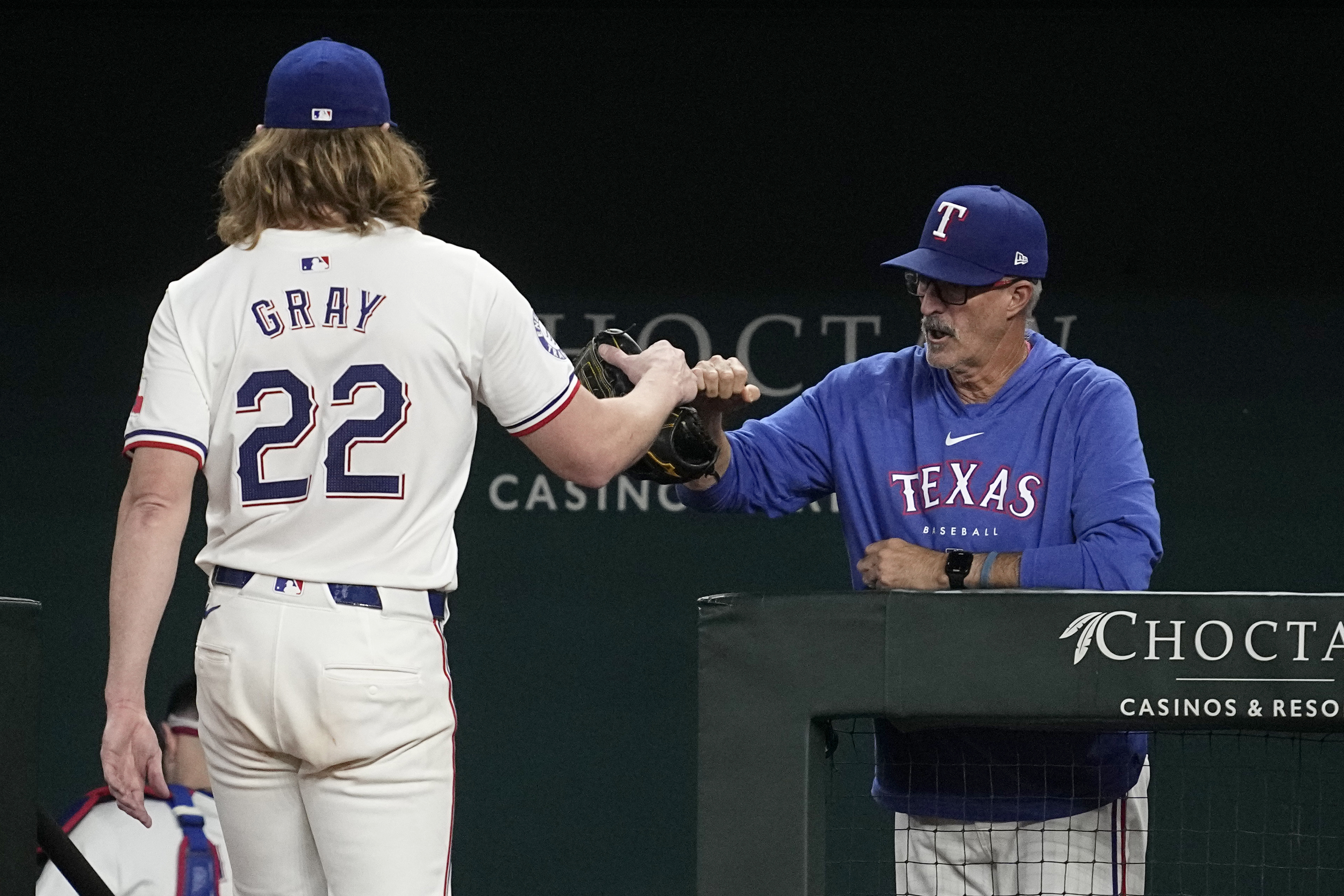 Texas Rangers' Jon Gray is greeted at the dugout entrance by pitching coach Mike Maddux after Gray threw to the Chicago White Sox in the sixth inning of a baseball game, Tuesday, July 23, 2024, in Arlington, Texas. 