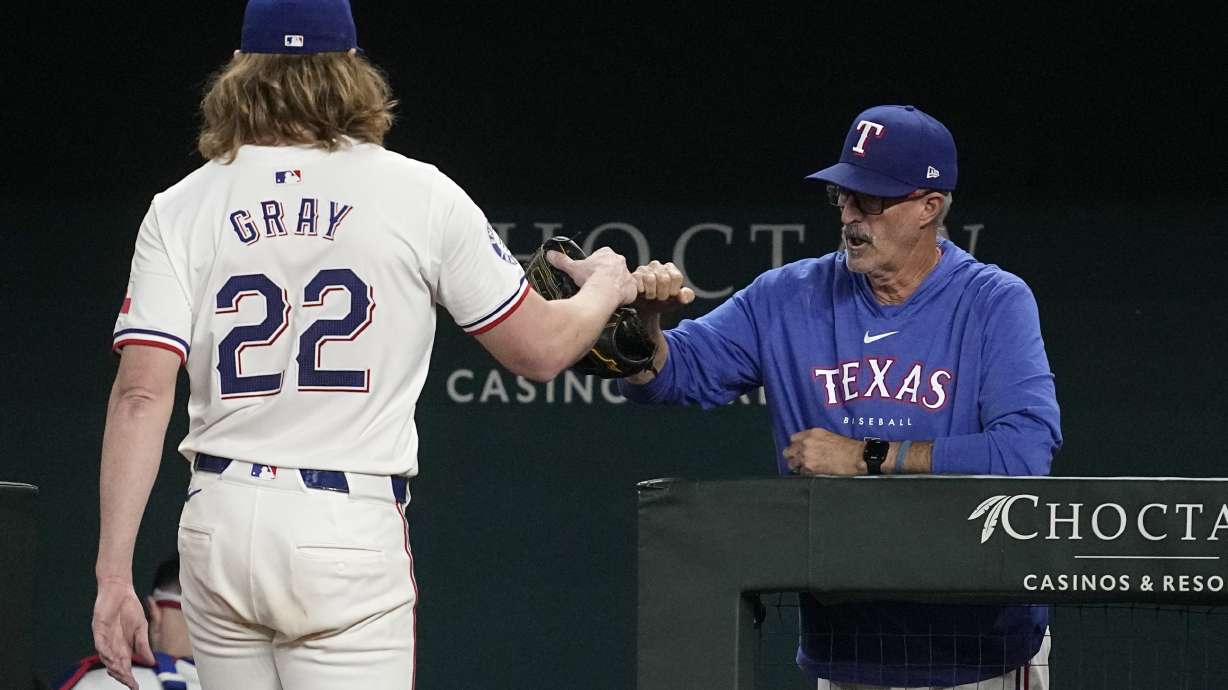 Texas Rangers' Jon Gray is greeted at the dugout entrance by pitching coach Mike Maddux after Gray threw to the Chicago White Sox in the sixth inning of a baseball game, Tuesday, July 23, 2024, in Arlington, Texas.