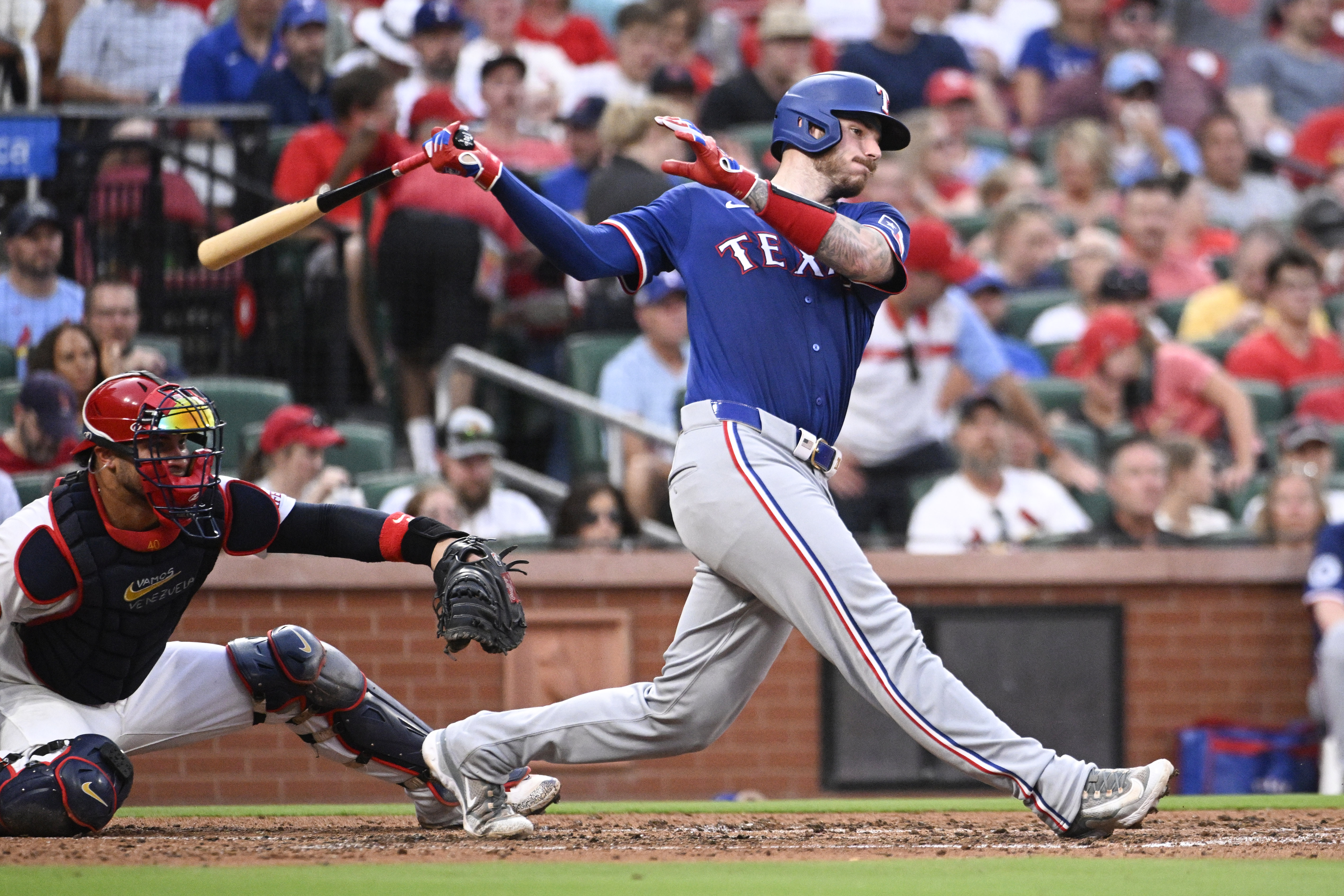 Texas Rangers' Jonah Heim, right, watches his RBI single next to St. Louis Cardinals catcher Willson Contreras in the fourth inning of a baseball game, Monday, July 29, 2024, in St. Louis. 