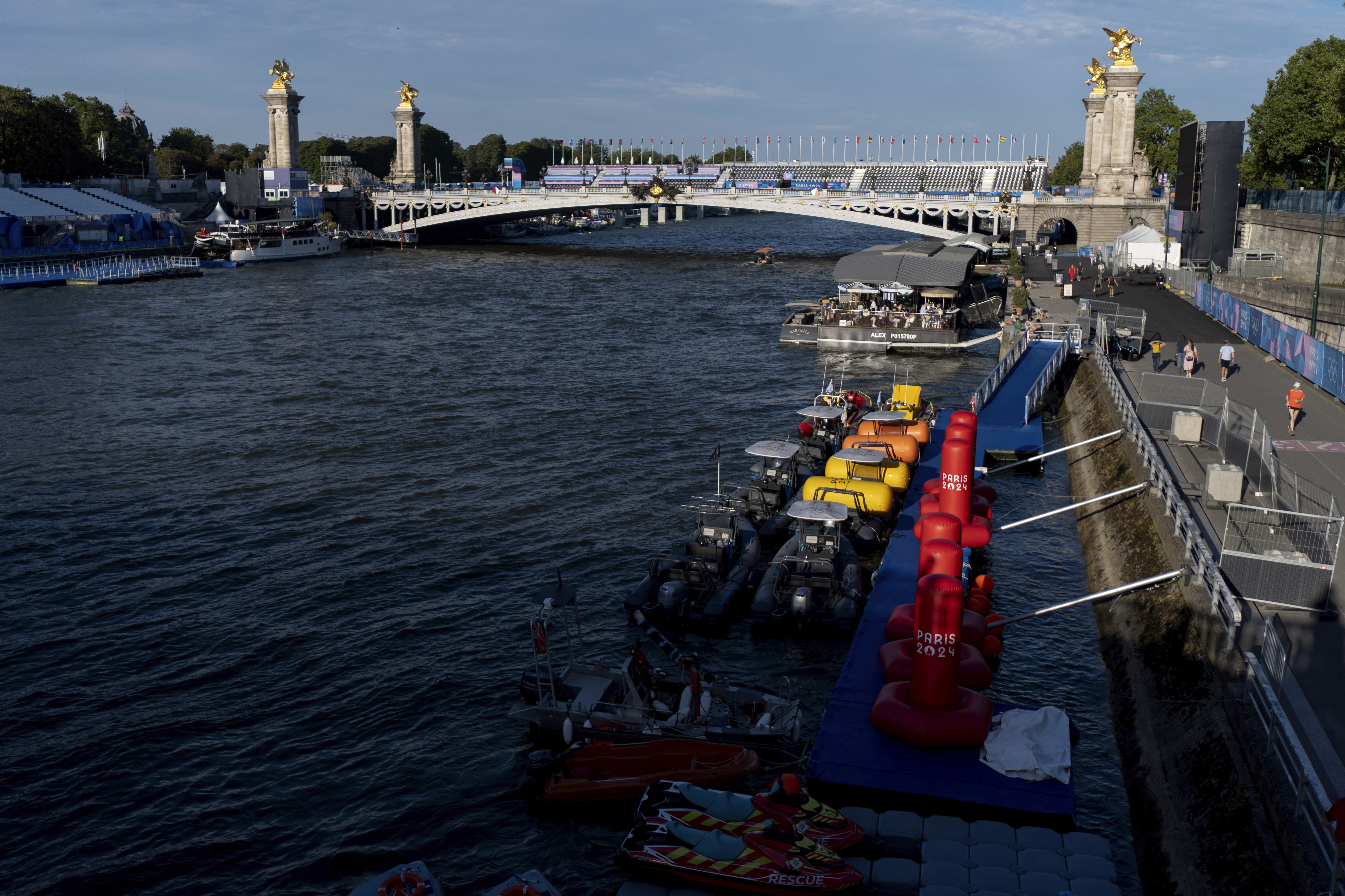 Watercraft and buoys sit along the Seine river as the triathlon event venue on the Pont Alexandre III bridge stands in the background at the 2024 Summer Olympics, Sunday, July 28, 2024, in Paris. 