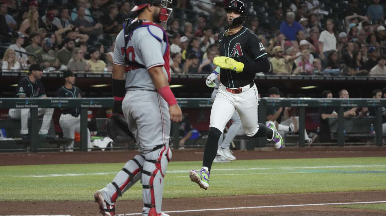 Arizona Diamondbacks' Lourdes Gurriel Jr., right, runs to score against the Washington Nationals on a double hit by Kevin Newman in the fourth inning during a baseball game, Monday, July 29, 2024, in Phoenix.