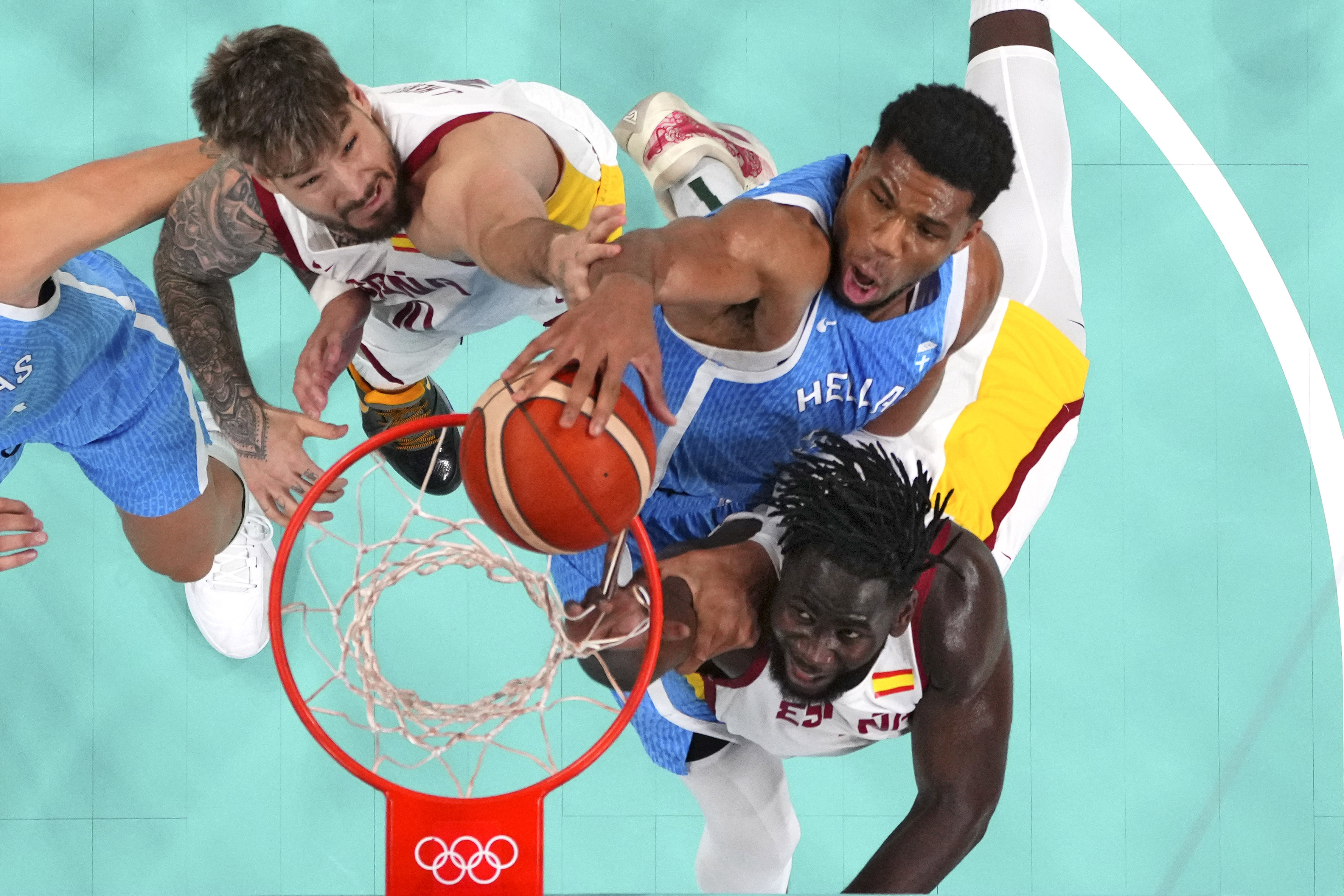 Giannis Antetokounmpo, center, of Greece, dunks as Juancho Hernangomez, of Spain, and Usman Garuba, left, of Spain, defend at the 2024 Summer Olympics, Tuesday, July 30, 2024, in Villeneuve-d'Ascq, France.