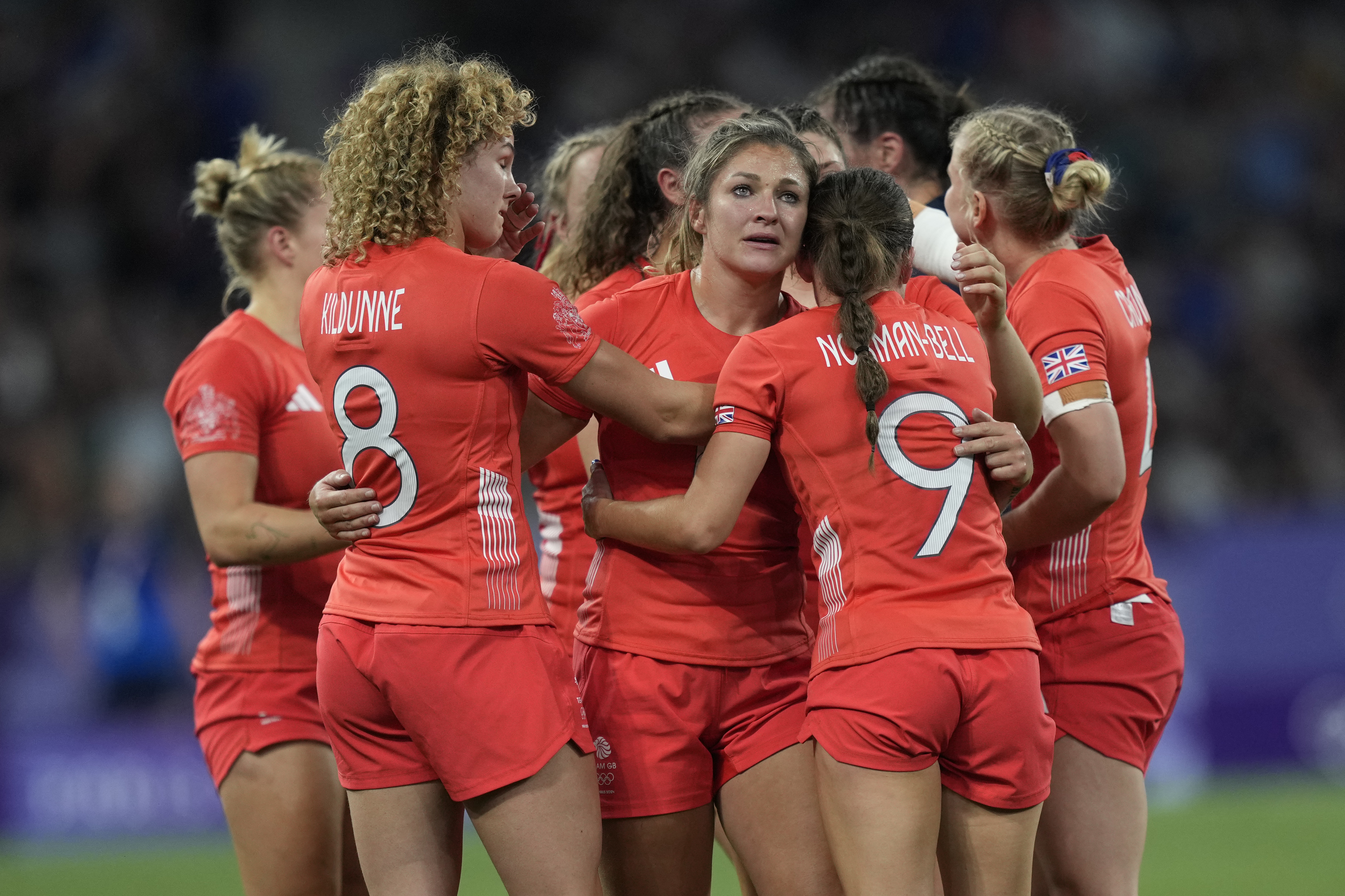 Great Britain's Amy Wilson Hardy, center joins her teammates in a huddle after they lost their women's quarterfinal Rugby Sevens match between Great Britain and the United States at the 2024 Summer Olympics, in the Stade de France, in Saint-Denis, France, Monday, July 29, 2024. The US won the game 17-7. 