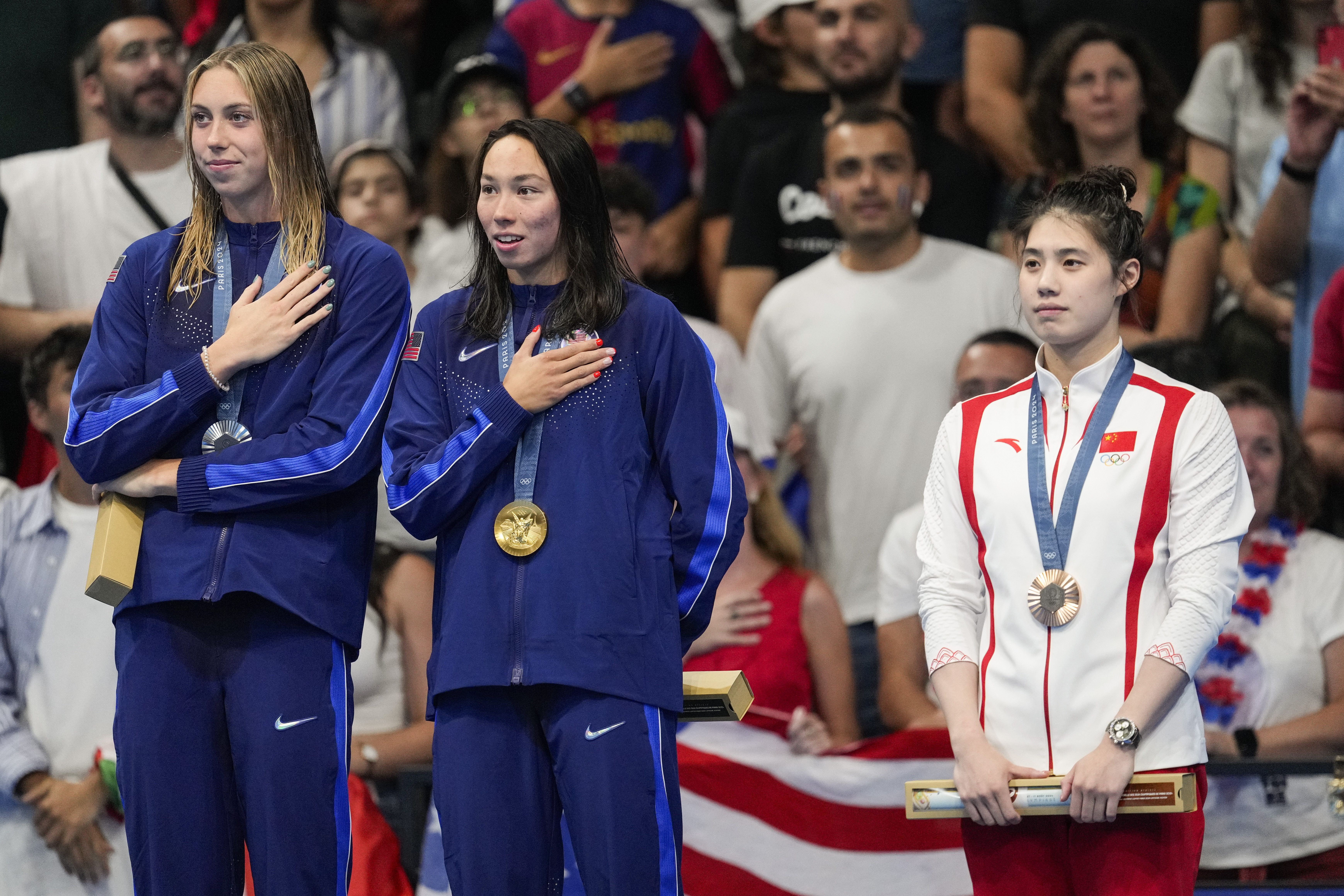 Gold medalist, Torri Huske, center, of the United States, stands with silver medalist, Gretchen Walsh, left, of the United States, and bronze medalist Zhang Yufei, of China, on the podium after the women's 100-meter butterfly final at the 2024 Summer Olympics, Sunday, July 28, 2024, in Nanterre, France. 