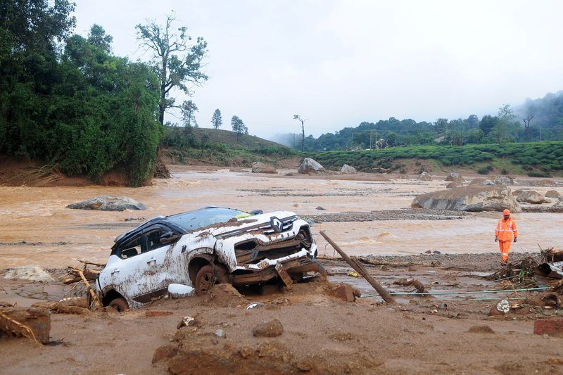 A rescuer walks past a damaged car at a landslide site after multiple landslides in the hills in Wayanad, in the southern state of Kerala, India, Tuesday.
