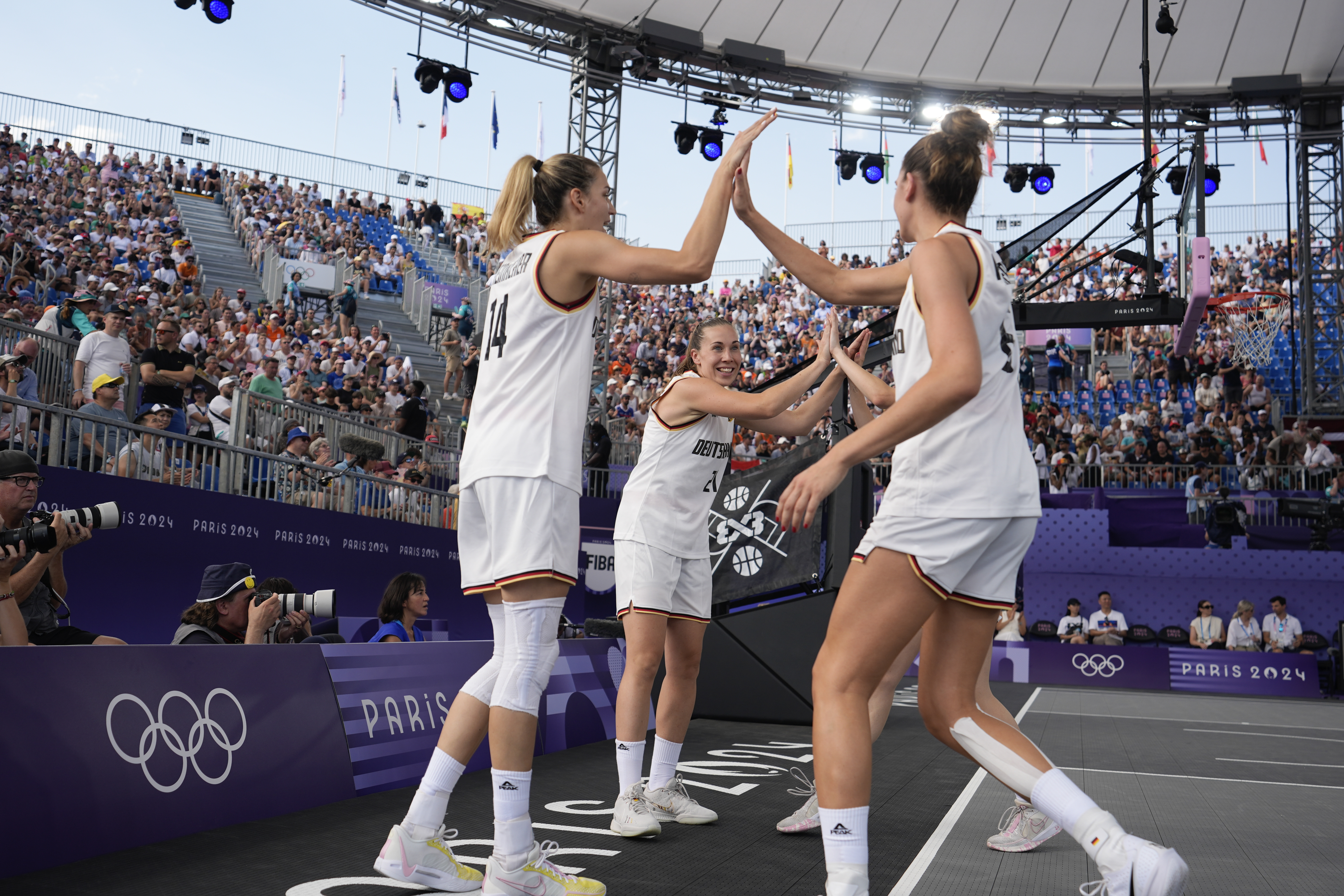 Svenja Brunckhorst of Germany, center, and teammates high five at the start of the women's 3x3 basketball pool round match between Germany and the United States at the 2024 Summer Olympics, Tuesday, July 30, 2024, in Paris, France.