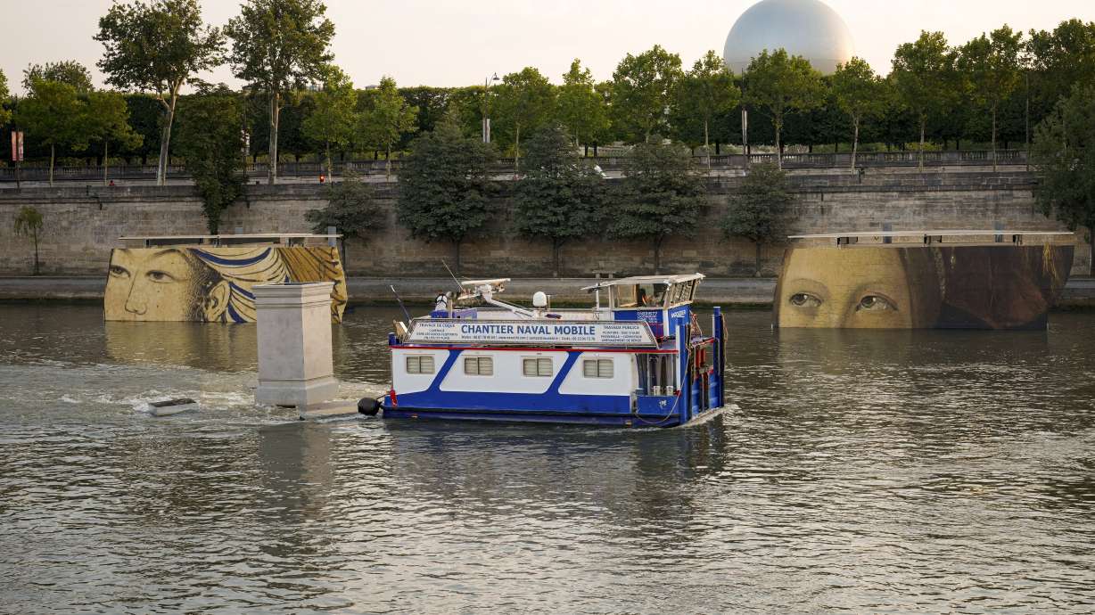 A boat sails past reproductions of artworks decorating the banks of the River Seineat the 2024 Summer Olympics, Tuesday, July 30, 2024, in Paris, France. The men's Olympic triathlon has been postponed over concerns about water quality in Paris' Seine River, where the swimming portion of the race was supposed to take place.