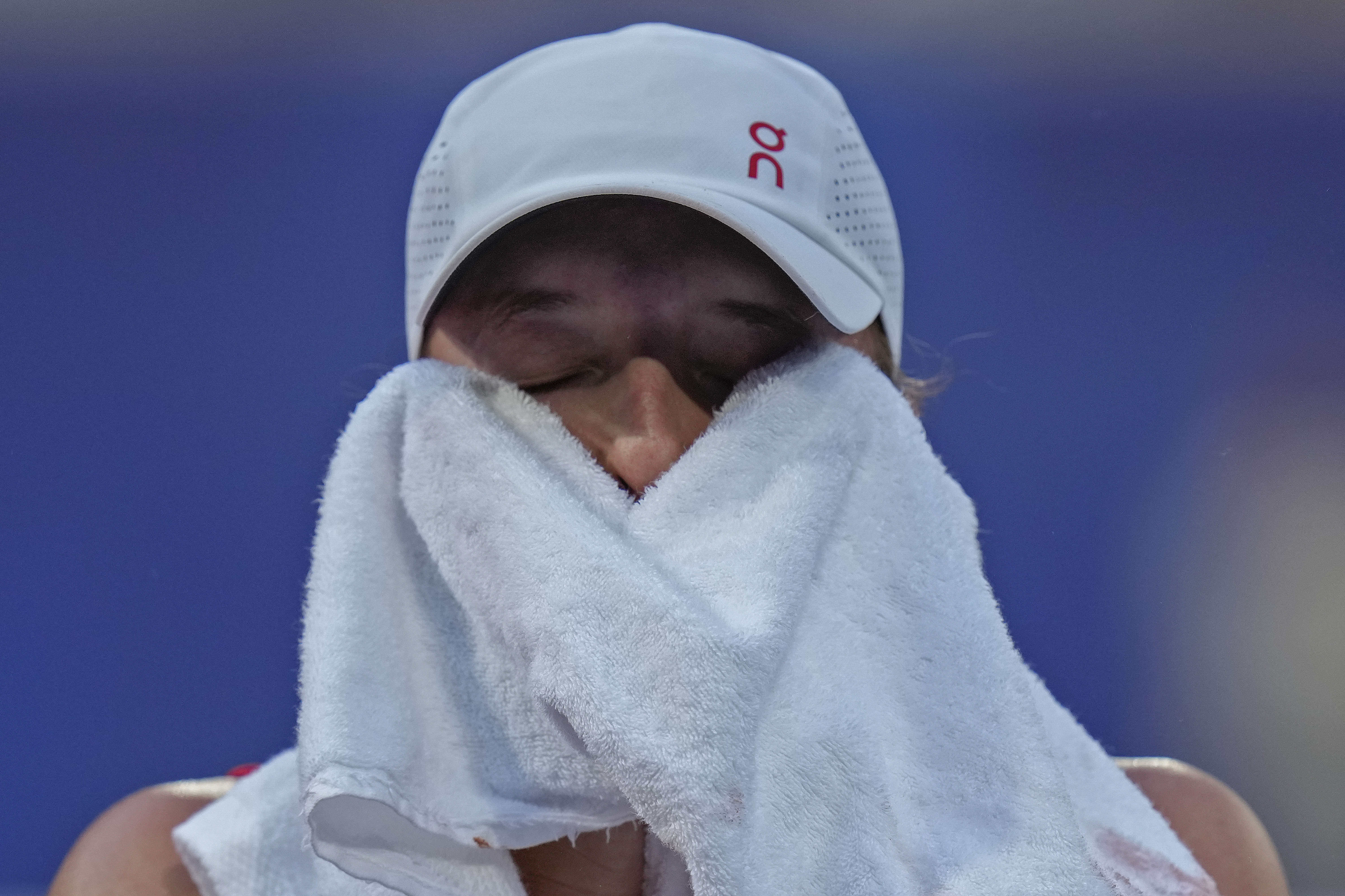 Iga Swiatek of Poland wipes her sweat as she plays Wang Xiyu of China during their women's singles third round match at the Roland Garros stadium, at the 2024 Summer Olympics, Tuesday, July 30, 2024, in Paris, France. 