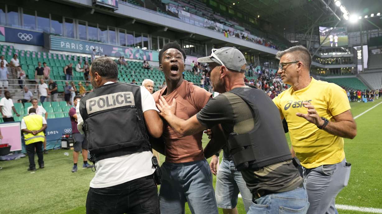 Security guards grab a pitch invader during the men's Group A soccer match between the United States and Guinea at Geoffroy-Guichard Stadium during the 2024 Summer Olympics, Tuesday, July 30, 2024, in Saint-Etienne, France.
